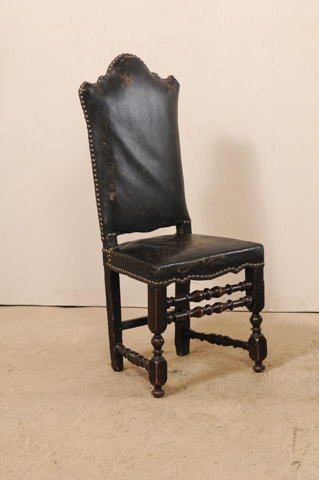 A pair of Italian leather and walnut side chairs from the 18th century. This antique pair of hall chairs from Italy feature tall shapely backs with stylized arch chest rail, beautifully turned front legs and side stretchers, with double turned-wood