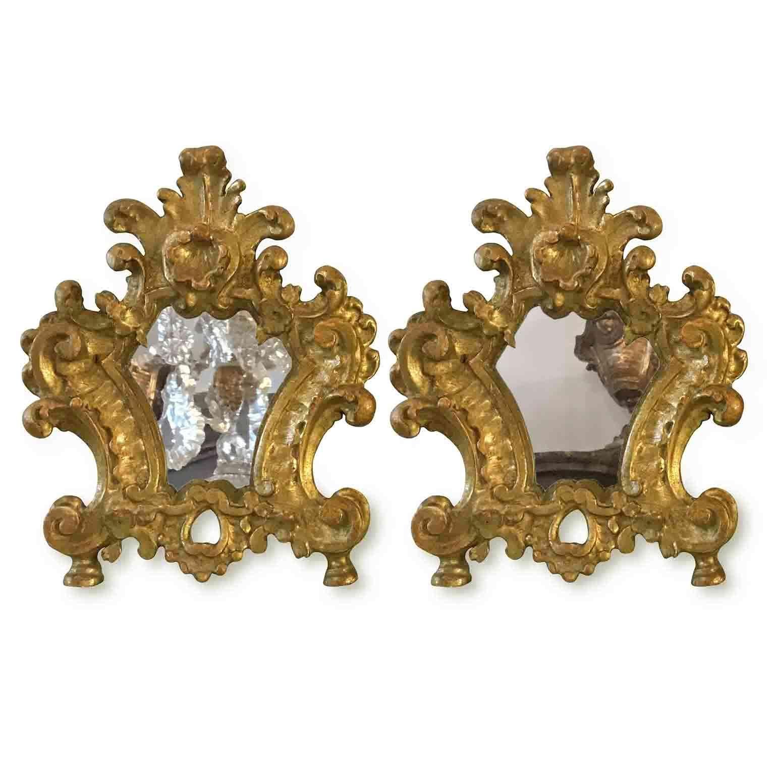 A charming pair of 18th century carved and giltwood mirrors, small altar cards or cantagloria from Italy. 
Shaped, with scrolling and vegetal deep carving, they are realized in cembran pinewood and have an original gold leaf gilding, dating back to