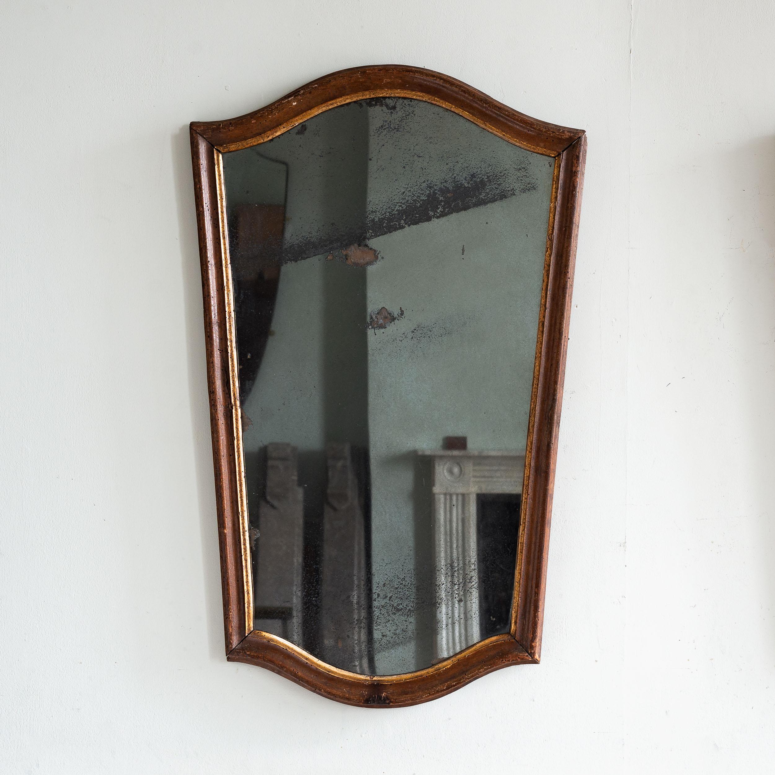 Pair of 18th century Italian Walnut wall mirrors, with gilding to the interior moulding surrounding the attractively foxed mercury mirror plates. Of striking and elegant tapered form, in usable condition showing sign of old (non-active) wood-worm
