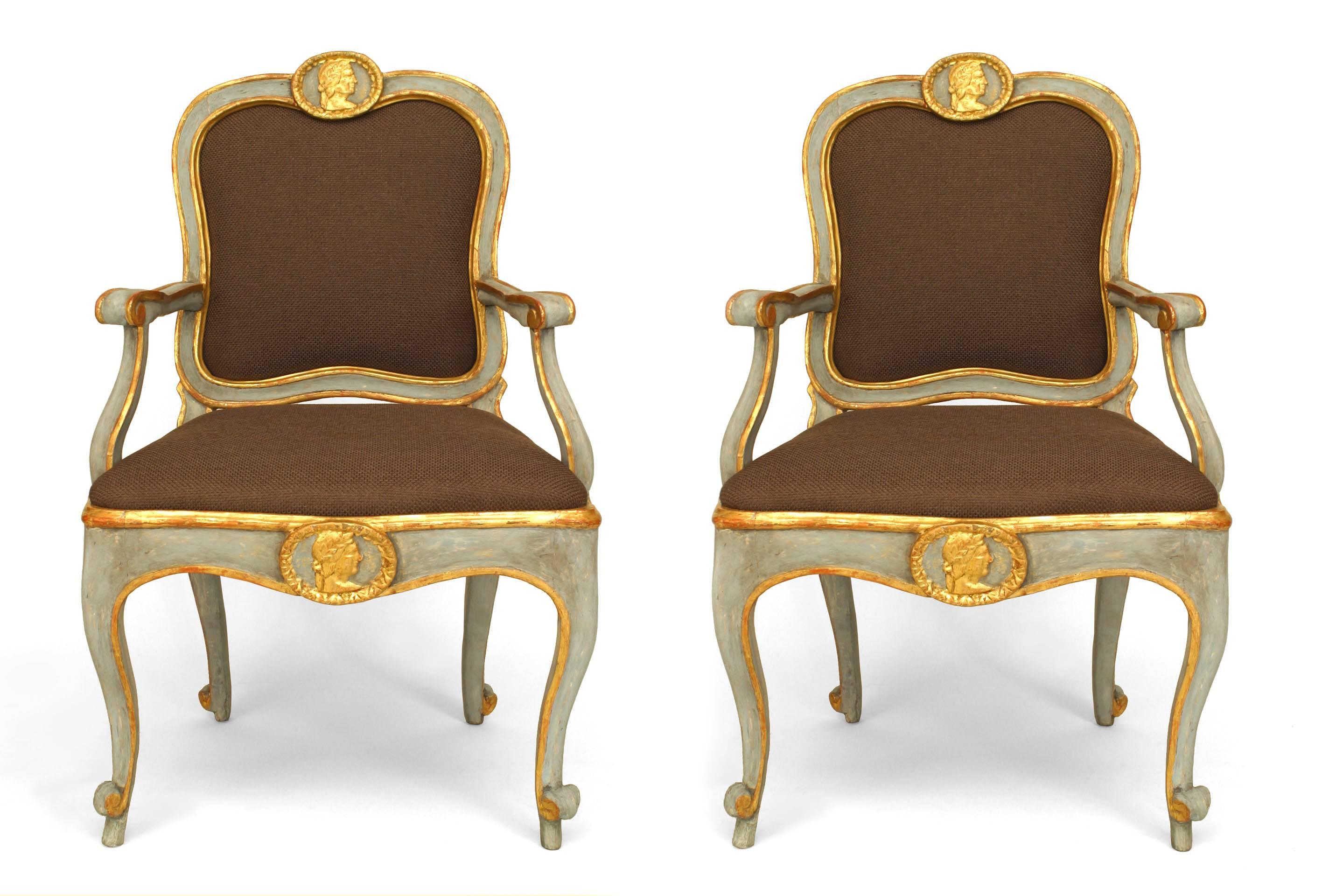 Pair of Italian neoclassic (Roman 18th century) blue painted and gilt trimmed arm
chairs with roundels carved with masks on each back and front seat rail. The chairs feature upholstered seats and backs.