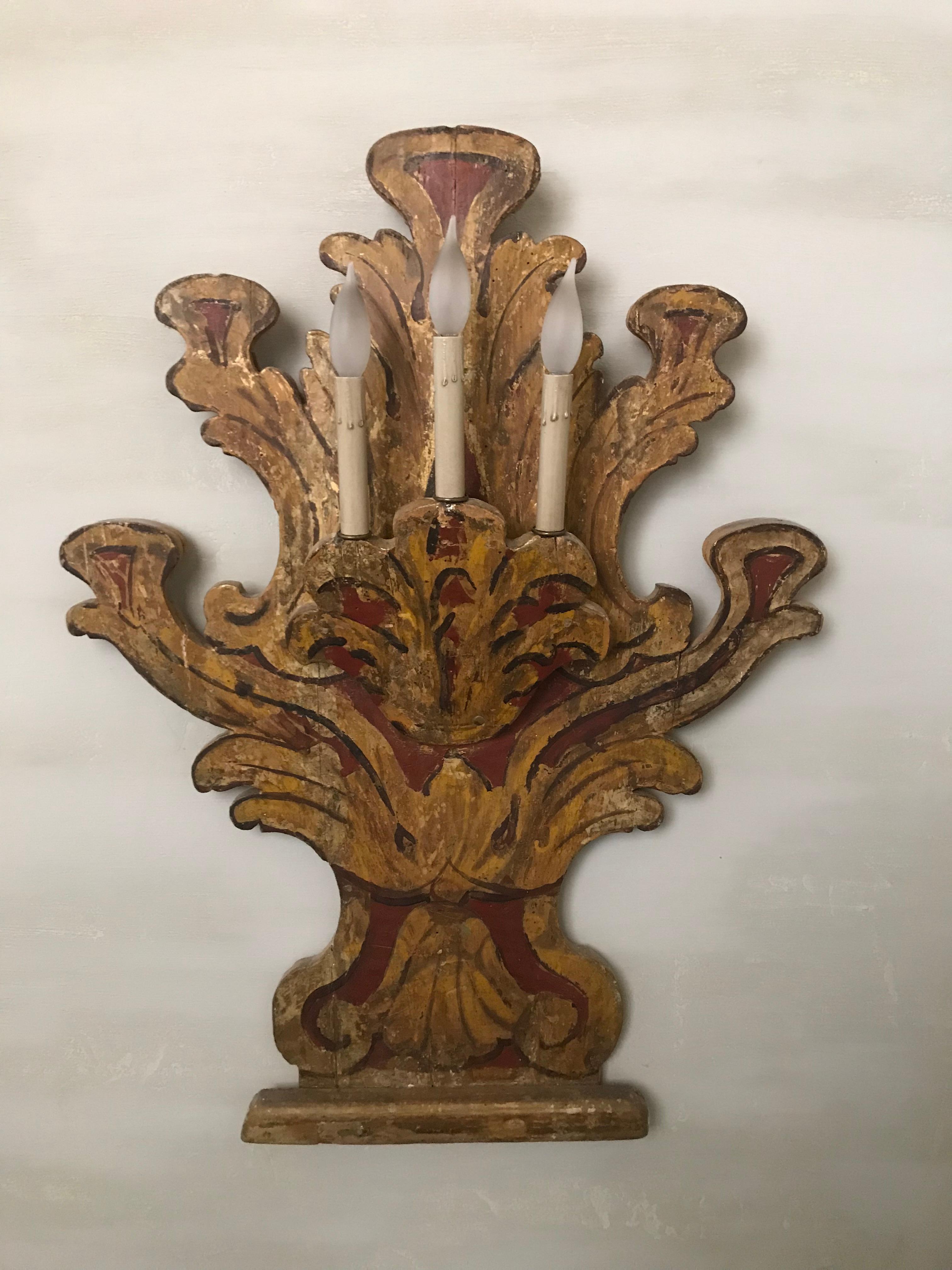 Pair of 18th century Italian sconces made of wood painted in shades of red and gold with black outlines. Each sconce has three candleholders. The sconces mount flat to the wall and ready for electrical installation. The shape is a cut-out curved
