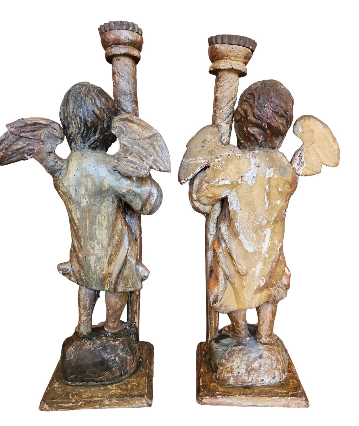 Jolie paire de Putti en bois sculpté italien qui tiennent des bougies.  La base est de 7
