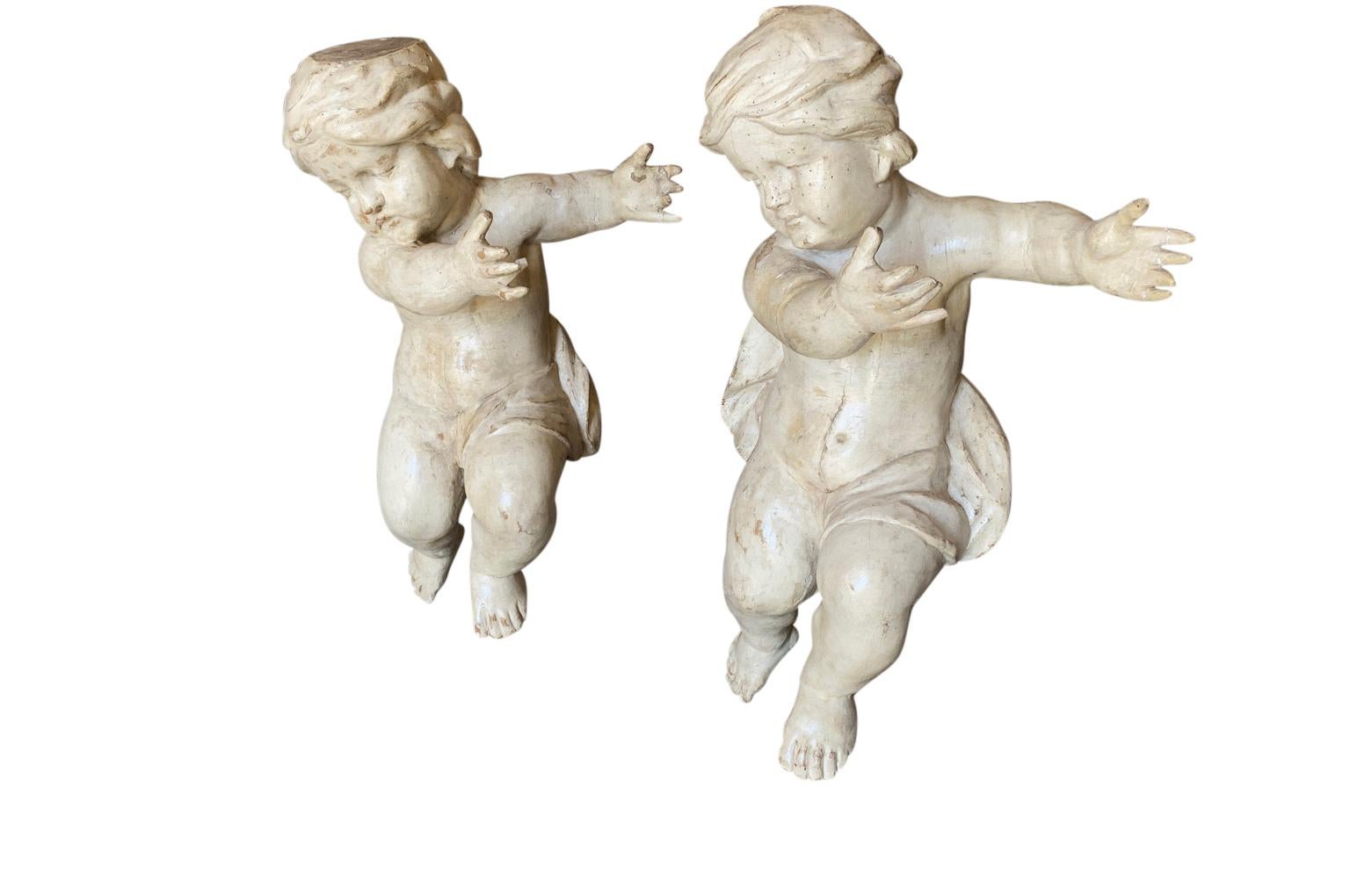 A stunning pair of mid-18th century Italian Baroque Putti beautifully crafted in polychromed wood - now resting on their iron stands. Charming position with outreached hands and sweet faces. On the backside of the head of one of the putti, there is