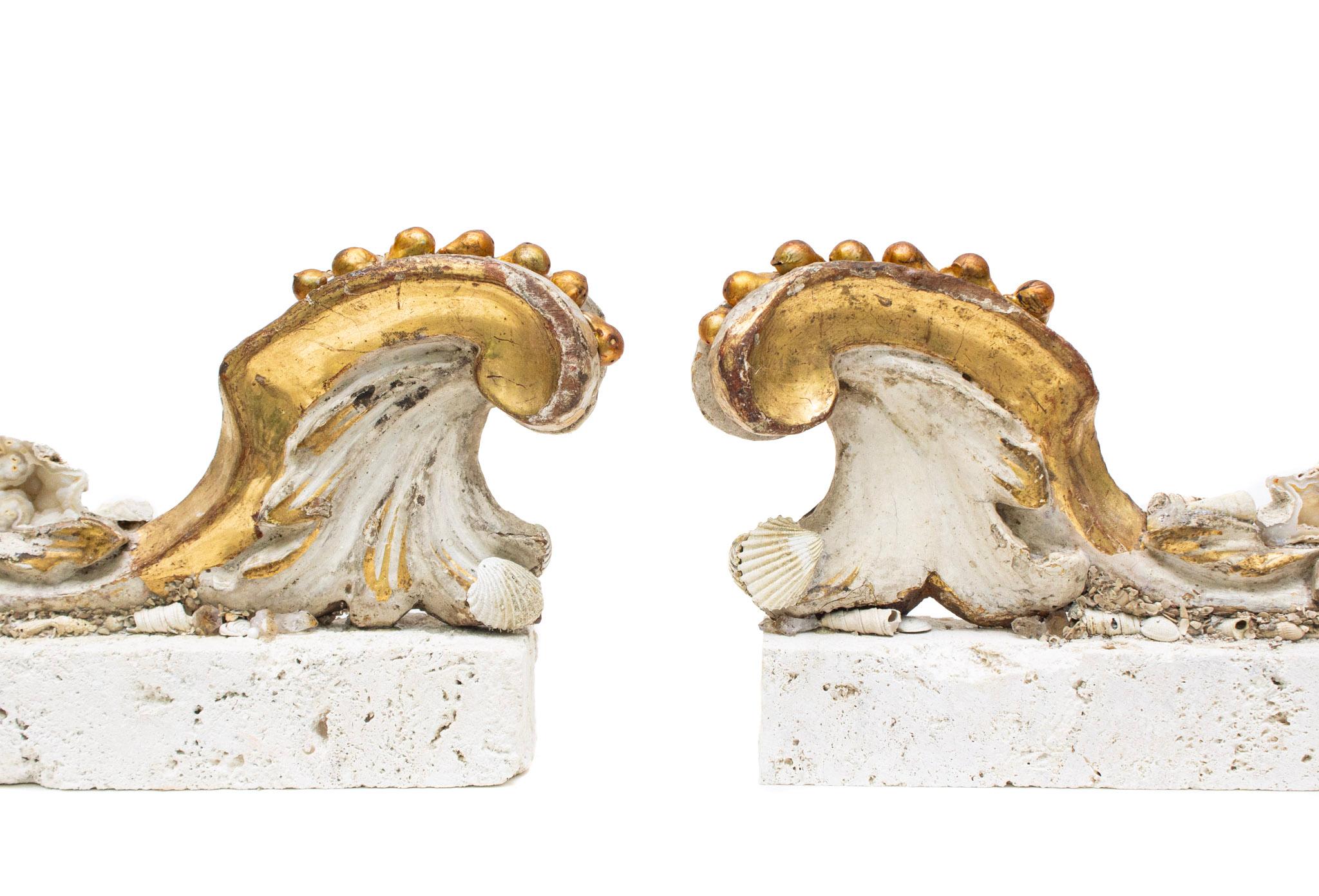 A pair of 18th-century Italian wood scroll fragments edged in gold leaf with gold leaf detailing and applied coordinating agate coral and fossil shells. The hand-carved gold leaf scrolls have natural forming gold baroque pearls and sit on a solid
