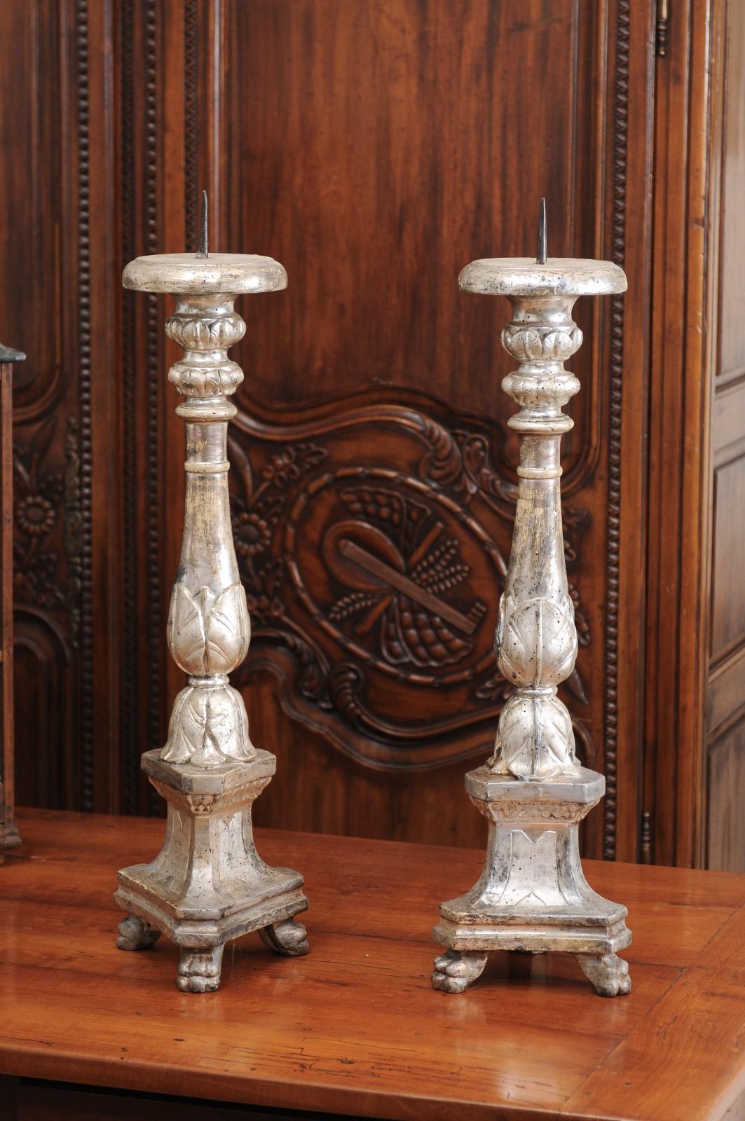 A pair of Italian silver gilt wooden candlesticks from the 18th century, with waterleaves and paw feet. Created in Italy during the 18th century, each of this pair of candlesticks is carved with delicate waterleaves and is resting on a tripod base