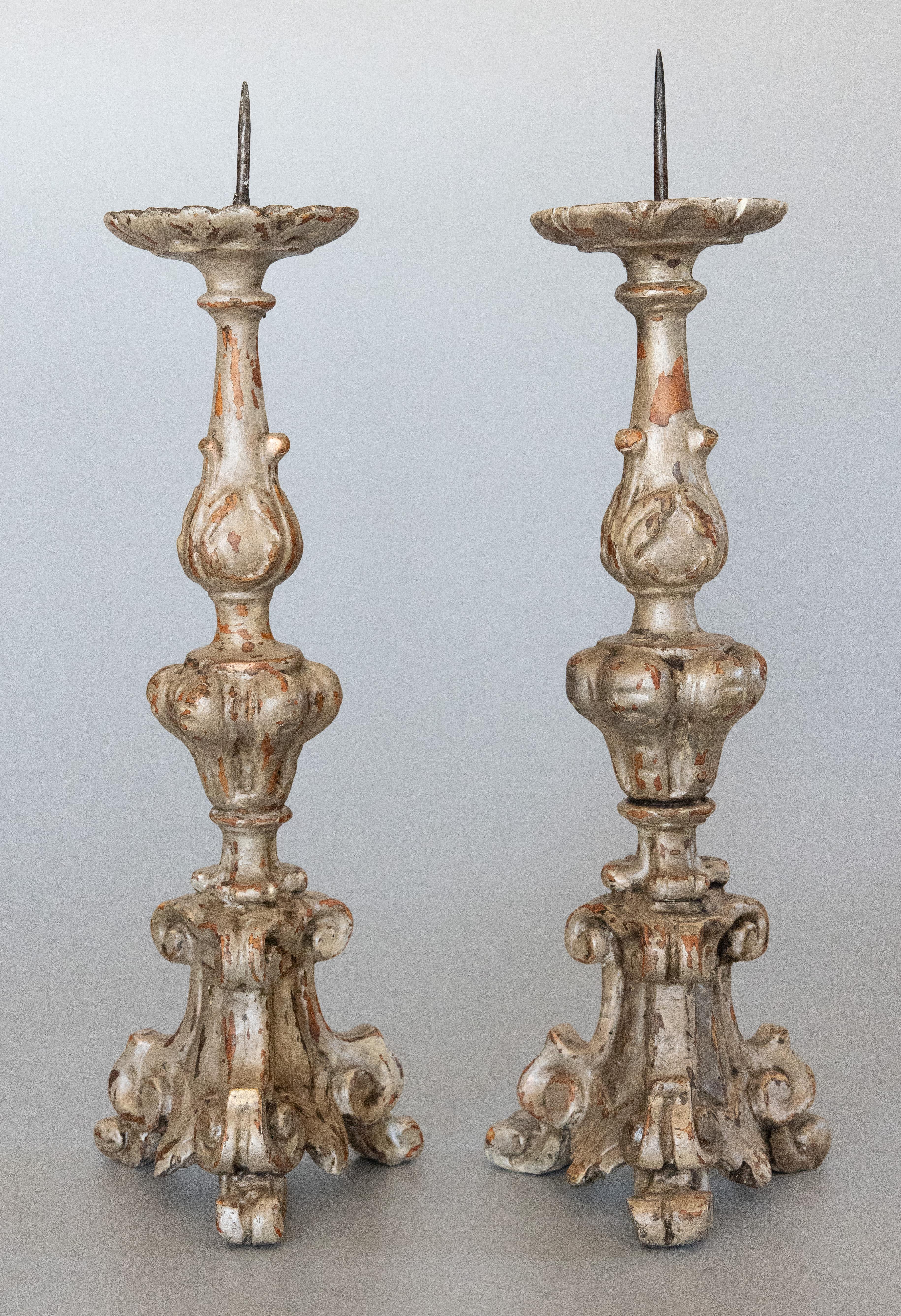 A stunning pair of antique 18th-Century Italian silvered wood tripod pricket altar candlesticks. These gorgeous cathedral candlesticks are a nice large size, silver gilded and ornately carved. They would be lovely displayed on a mantel or entry