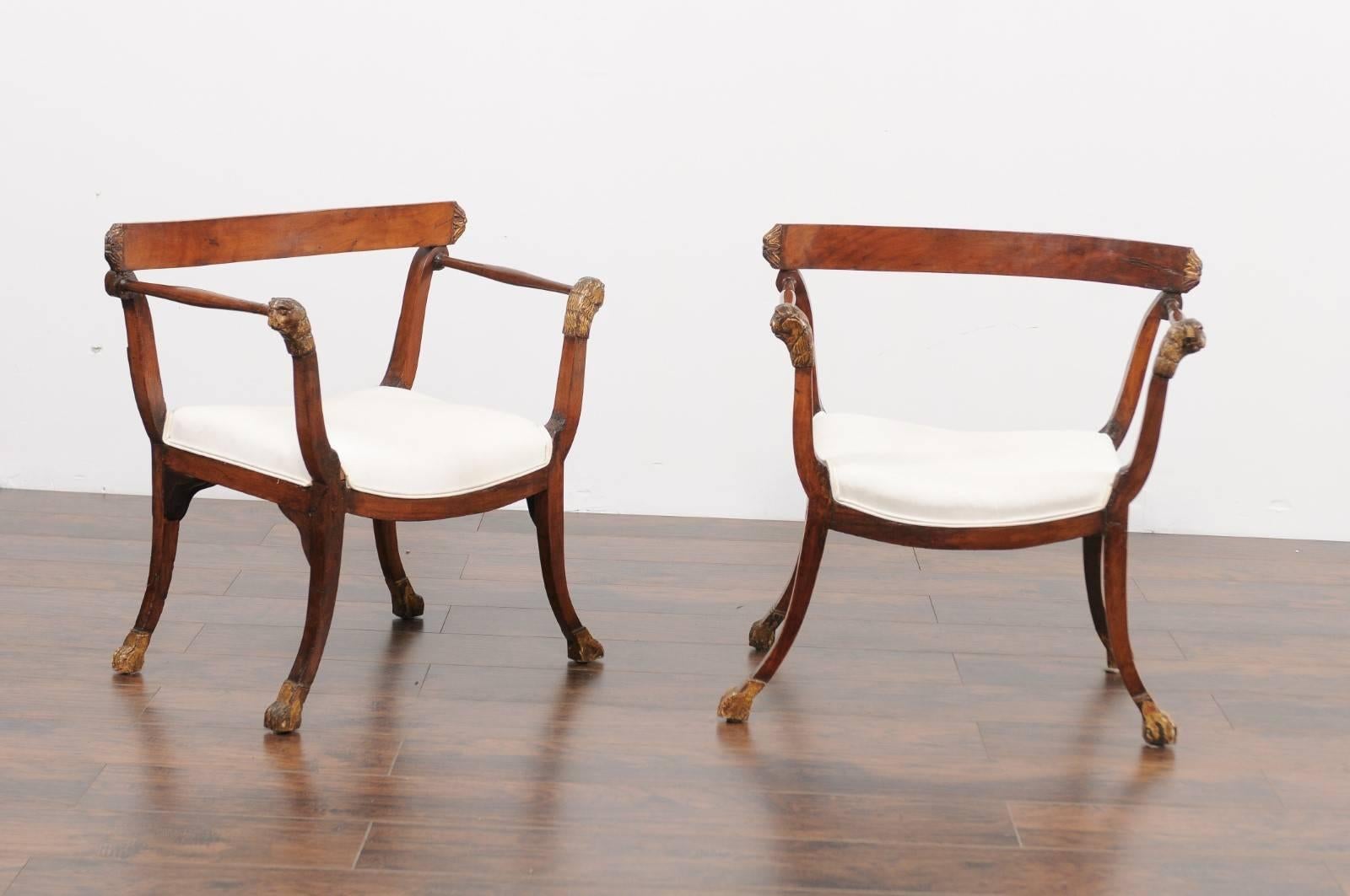 A pair of Italian walnut armchairs from the late 18th century. This pair of exquisite Italian chairs from circa 1790 features a simple and elegant curved top rail in the back, sitting over two discreet volutes. The upholstered seat supports two