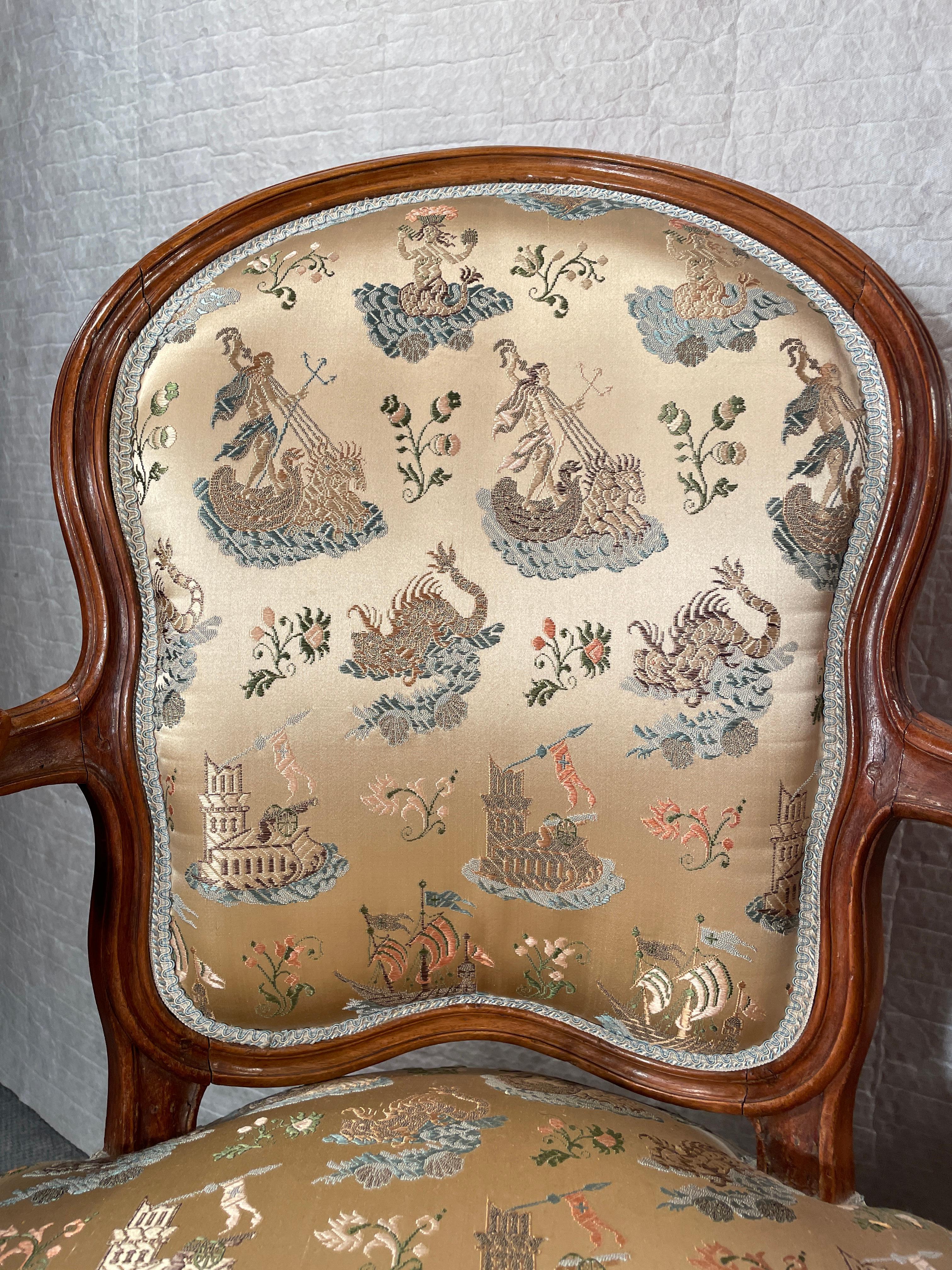 Entdecken Sie den zeitlosen Charme dieses exquisiten Louis XV-Sesselpaars, dessen anmutig geschwungene Nussbaumrahmen mit kunstvollen Schnitzereien verziert sind. Diese atemberaubenden Sessel sind in bemerkenswerter Weise in ihrem Originalzustand