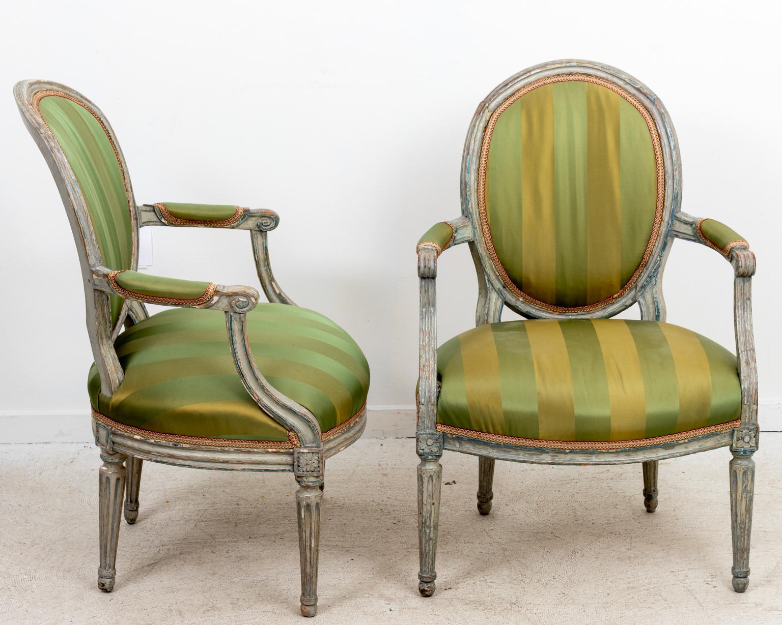 Circa 18th century pair of Louis XV style rounded back armchairs with upholstered seats and turned legs. Please note of wear consistent with age including distressed finish and paint loss to the wood frame.