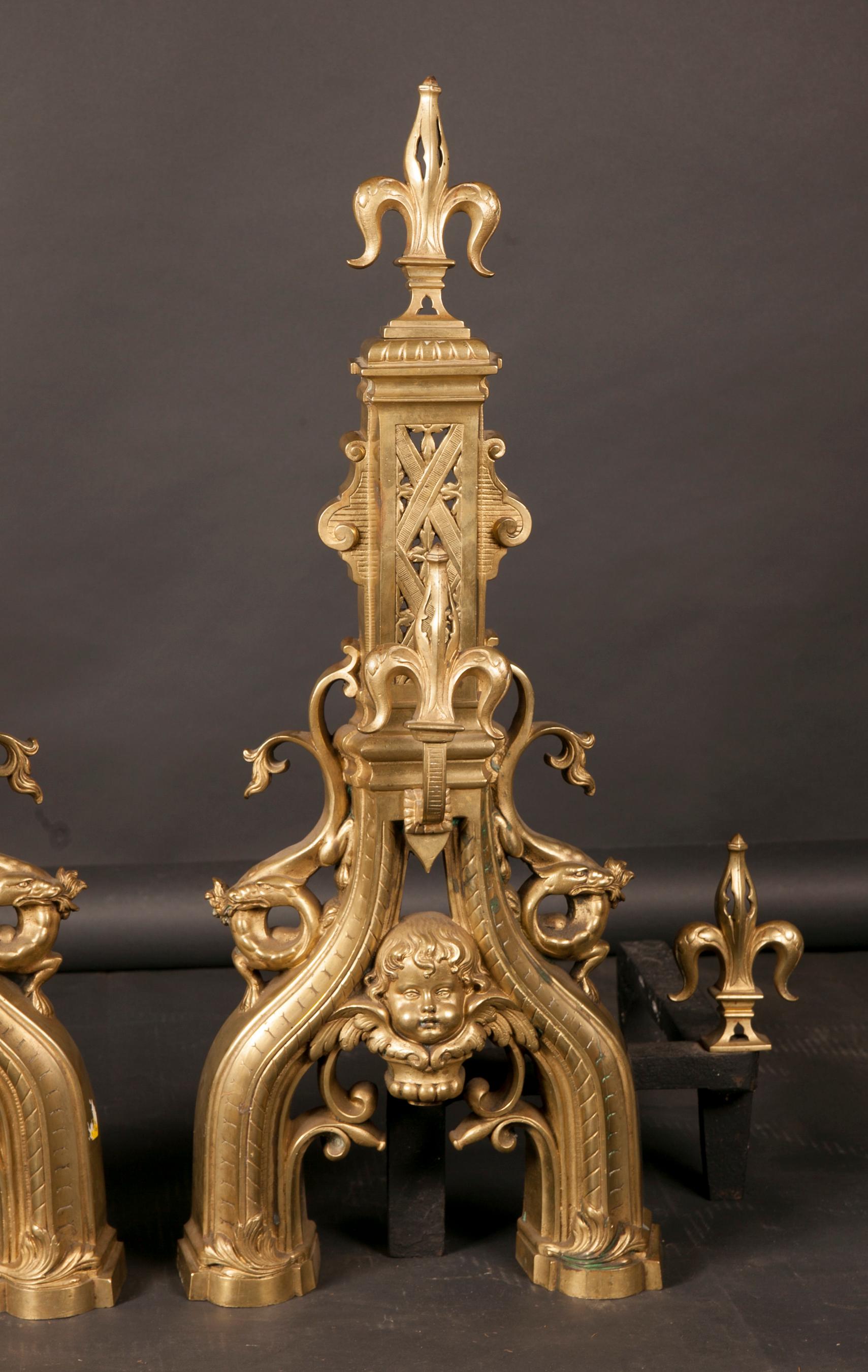 This fantastic pair of monumental French Louis XVI chenets are made of bronze and date back to the 18th century. The pair is adorned with Fleur de Lis at top, canter, and ends, and a single putti face is found at the centre of each. The bronze is