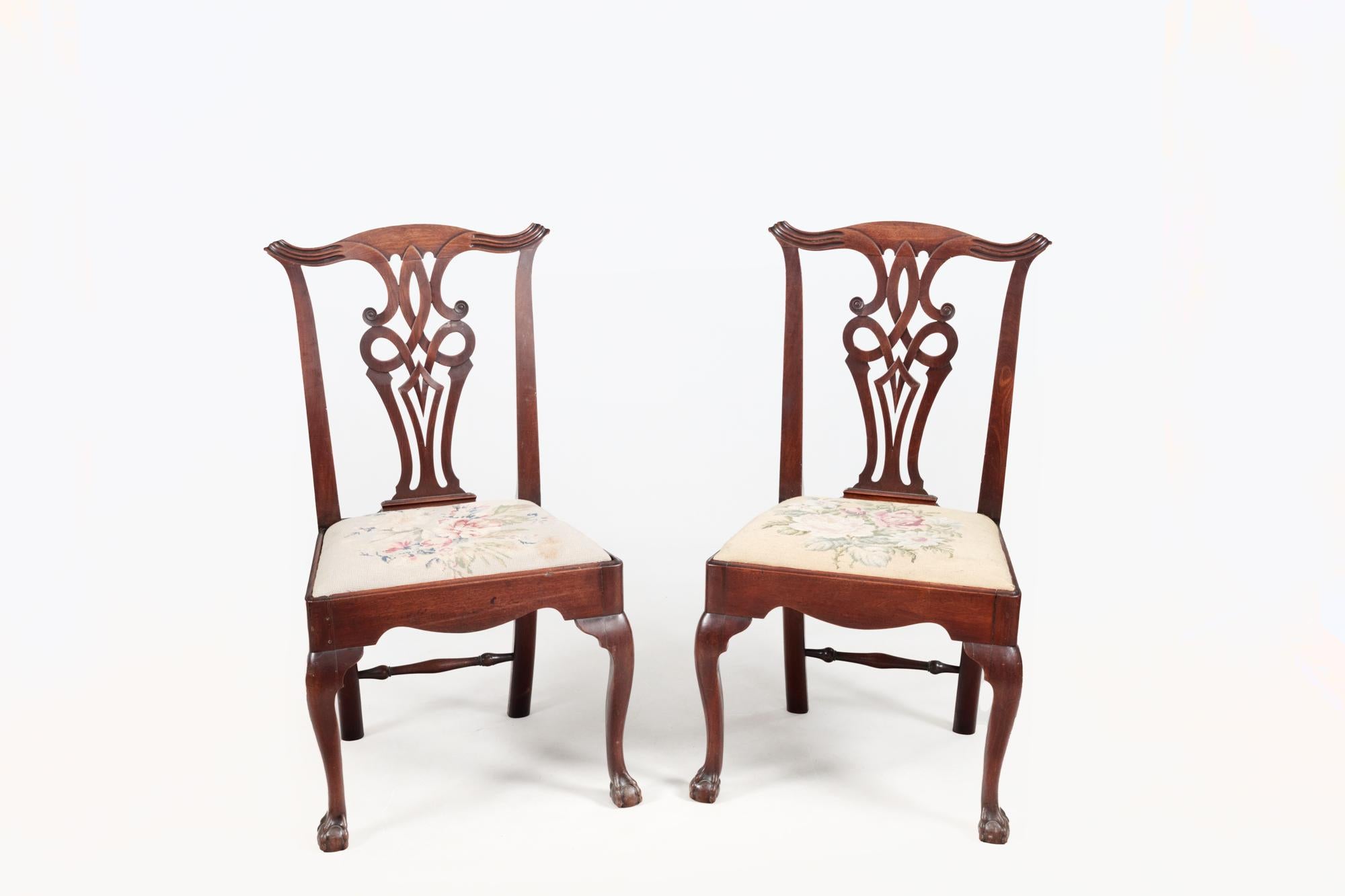 Pair of 18th Century mahogany Chippendale style chairs with interlaced back splats, fluted top rails, and simply shaped supports leading to embroidered padded seats. The front cabriole legs terminate with ball and claw feet and simple outswept legs