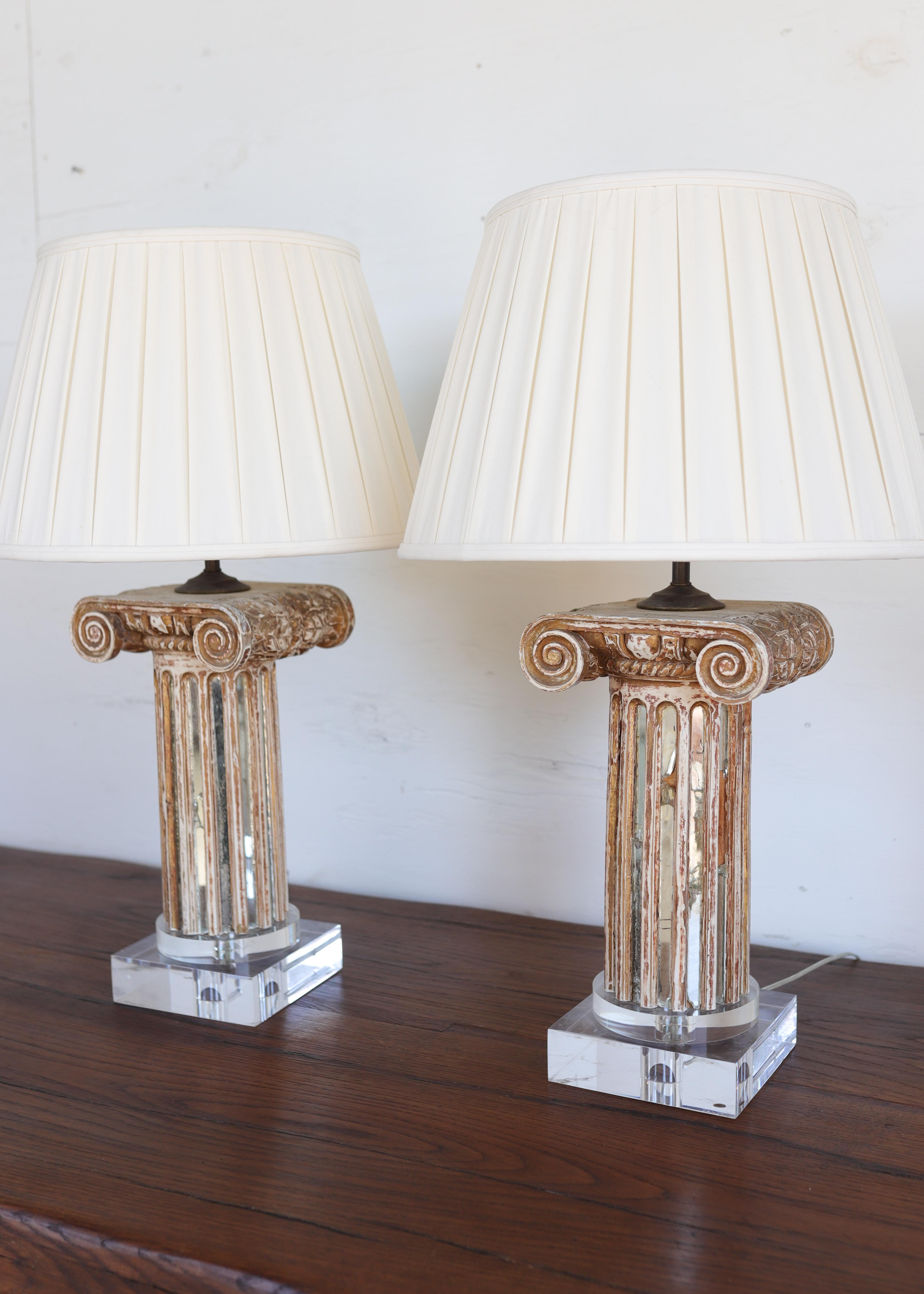 Squisita e scultorea, questa coppia di lampade del XVIII secolo evoca la grandezza dell'architettura classica. Ogni lampada è caratterizzata da una base a colonna in legno intagliata a mano e impreziosita da inserti in pannelli a specchio che