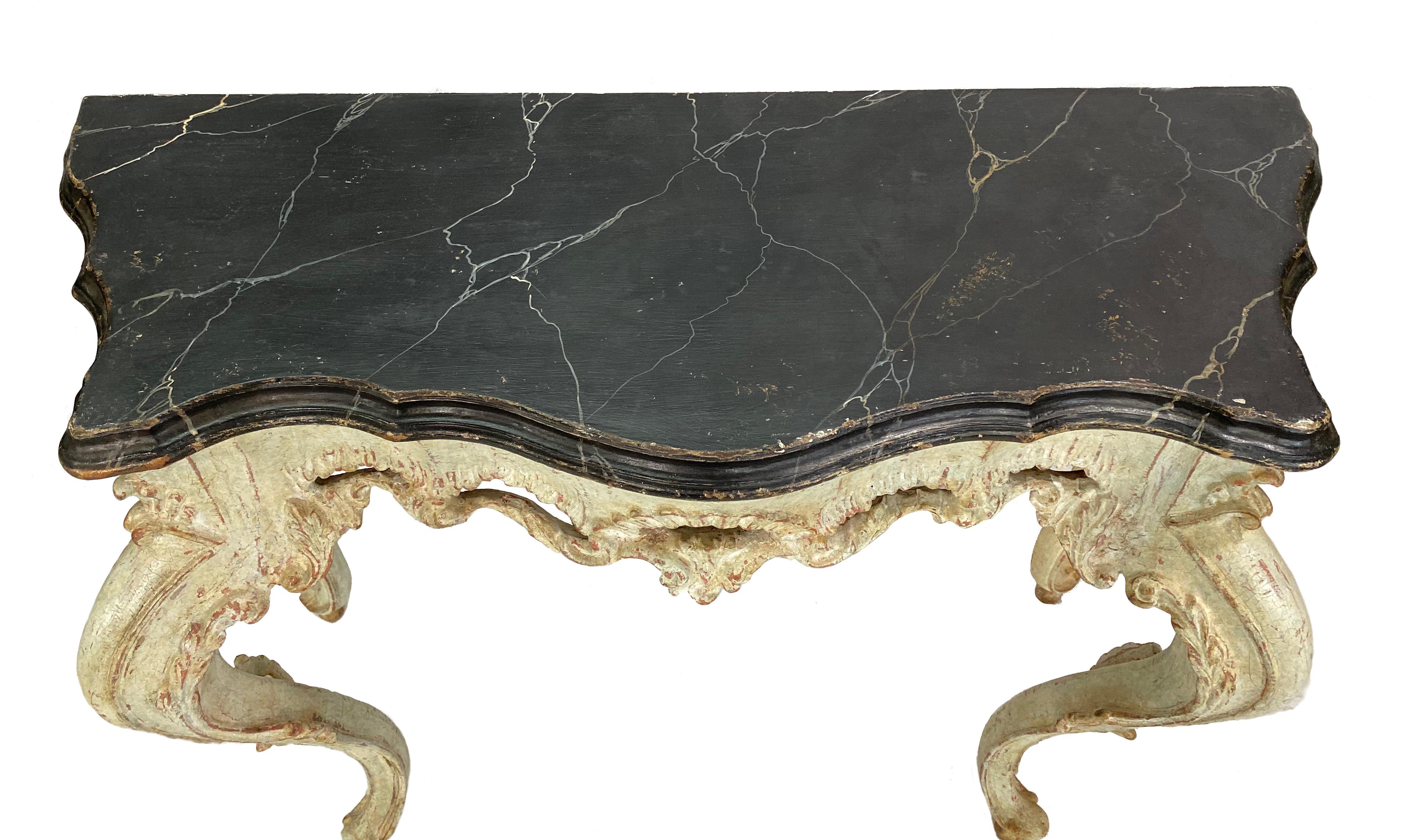 Stunning pair of 18th century painted Louis XV Italian consoles. The top is a painted black faux marble and the legs are a beautiful ivory with little flecks of red.