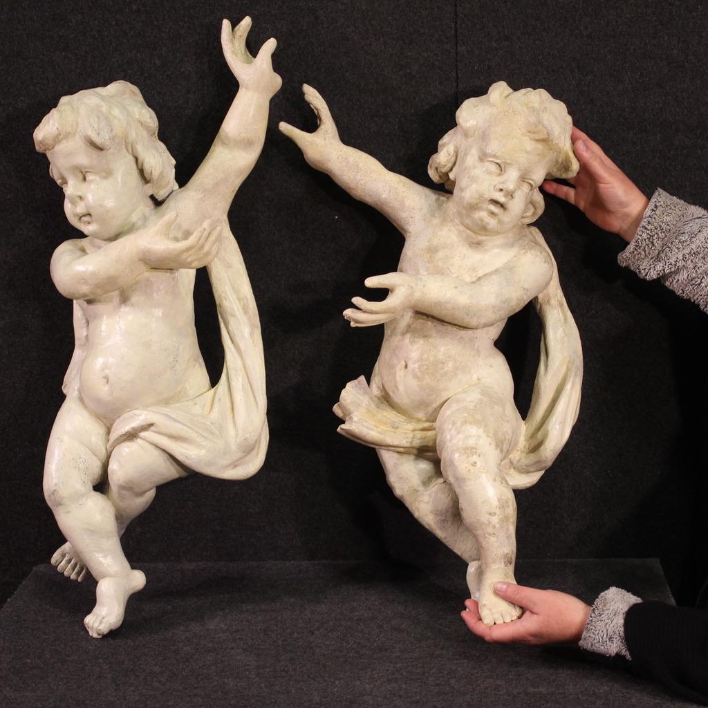 Pair of 18th century Italian sculptures. Wooden works of great size and impact, pleasantly carved, depicting cherubs. Sculptures painted in ivory color (not original painting, revived in the 20th century) of beautiful decoration. Works with mirrored