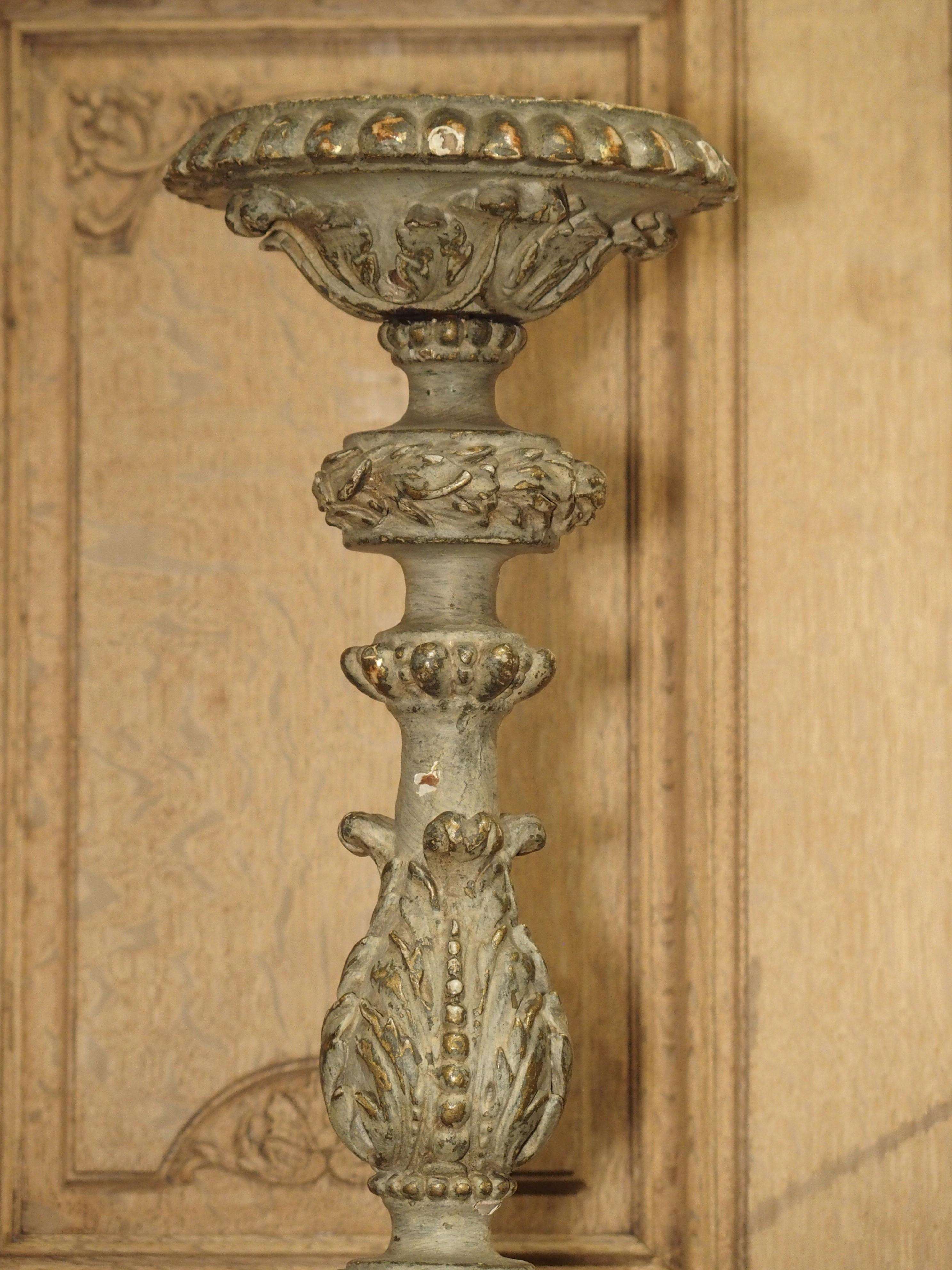 This pair of large French candlesticks from the 1700s has been masterfully hand carved. They retain their original grayish-green parcel paint where traces of the gesso and old gilding can be seen. The candlesticks alternate between rounded