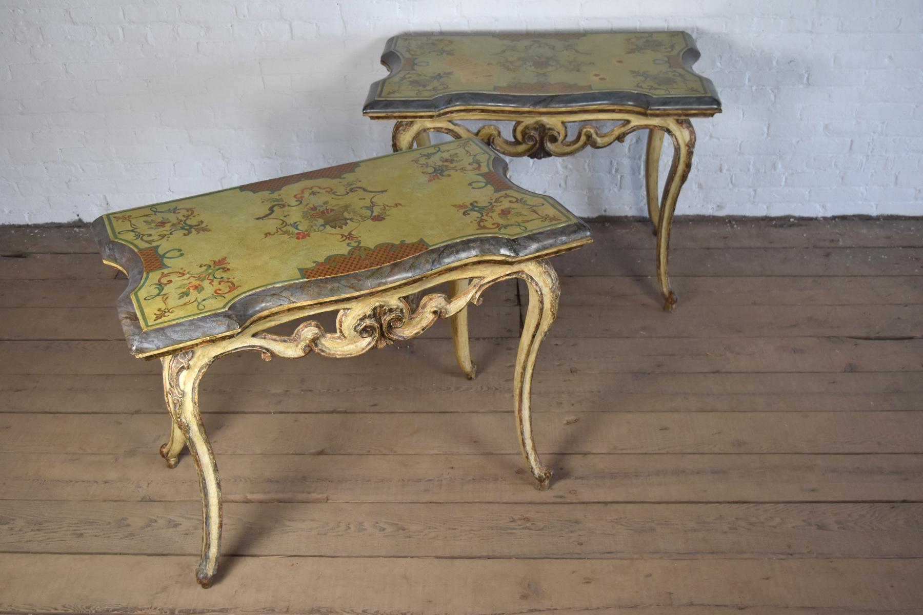 Sehr dekoratives und charmantes Paar Konsolentische italienischer Herkunft, die hölzernen versilberten und cremefarbenen Basen mit Kabriole Beinen und Scagliola Ornamenten tragen eine fröhlich bemalte Scagliola Tops in, signiert 