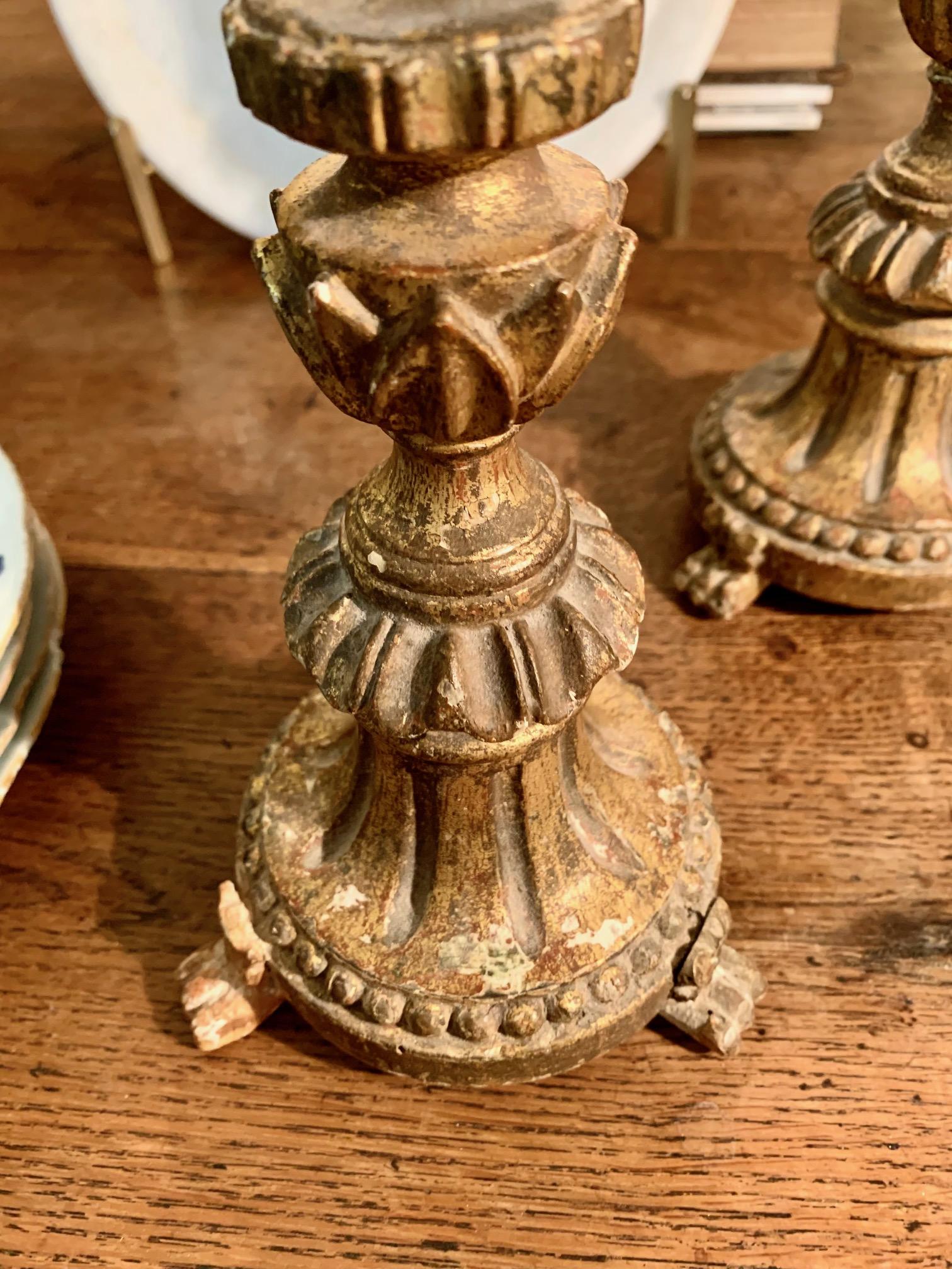 Une belle paire de chandeliers ou petits porte-torches d'époque baroque espagnole, ils faisaient sûrement partie du trousseau d'autel de l'église, en bois doré et sculpté à la main avec des restes de polychromie, ils reposent sur des pieds en
