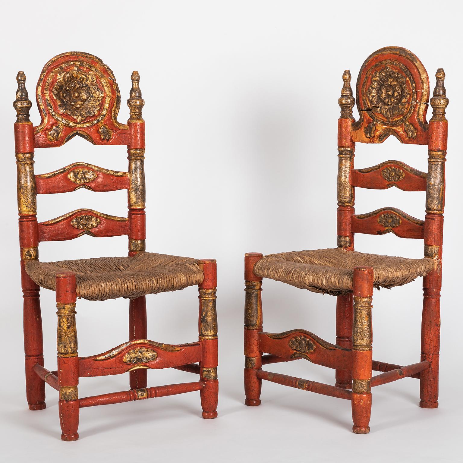 Beautiful and rare pair of Spanish Colonial style ladderback chairs hand painted in red and gold.
The wood from the structure is completely hand carved and the seating is handwoven rush.
As you can see on the pictures, one of the backs of the