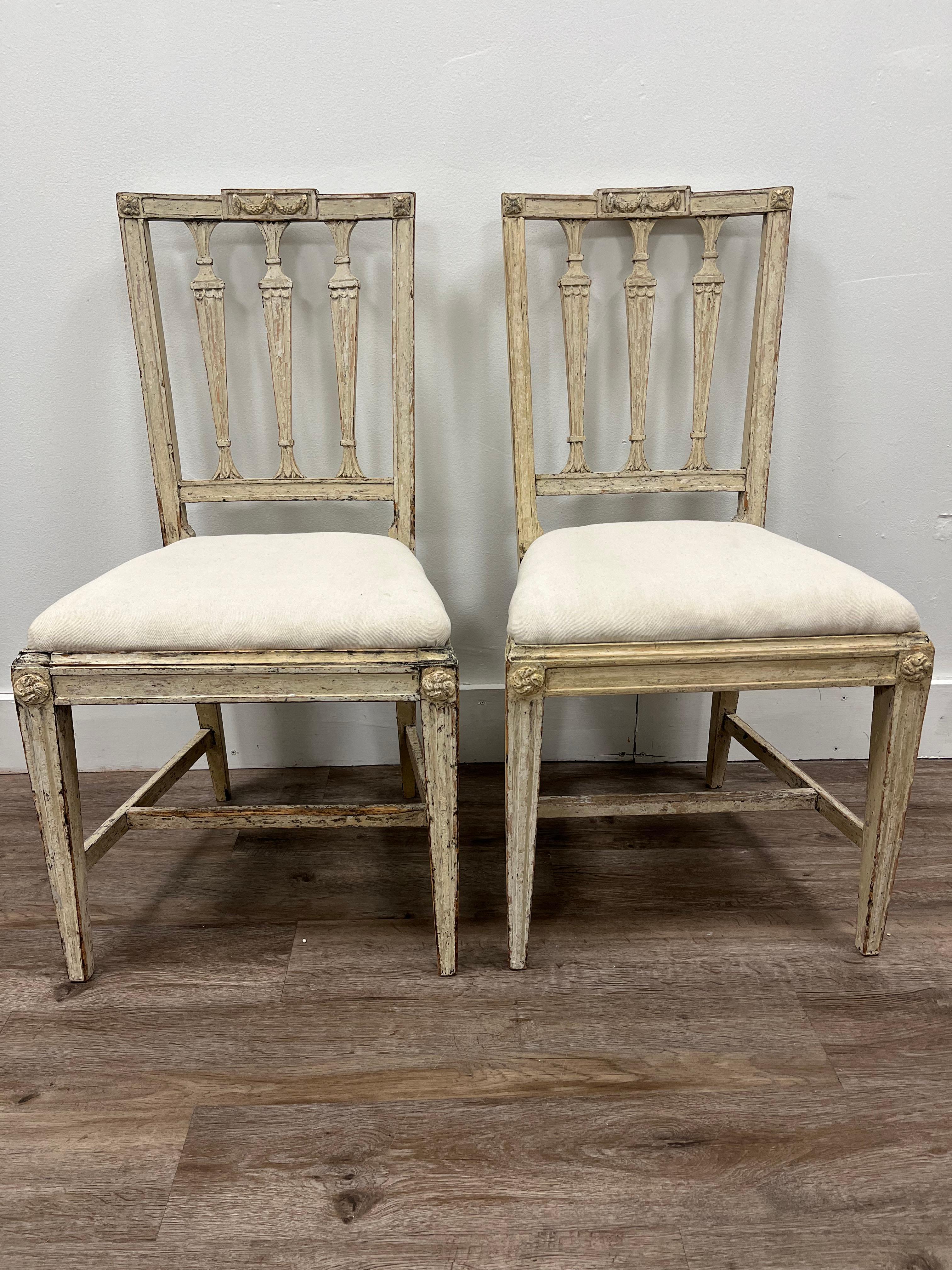 A pair of Gustavian chairs made in Stockholm by noted maker Johan Melchior Lundberg (active 1774 - 1812). One chair is signed MLB. Scraped to its well preserved original cream color. Original slip seats are reupholstered in linen.