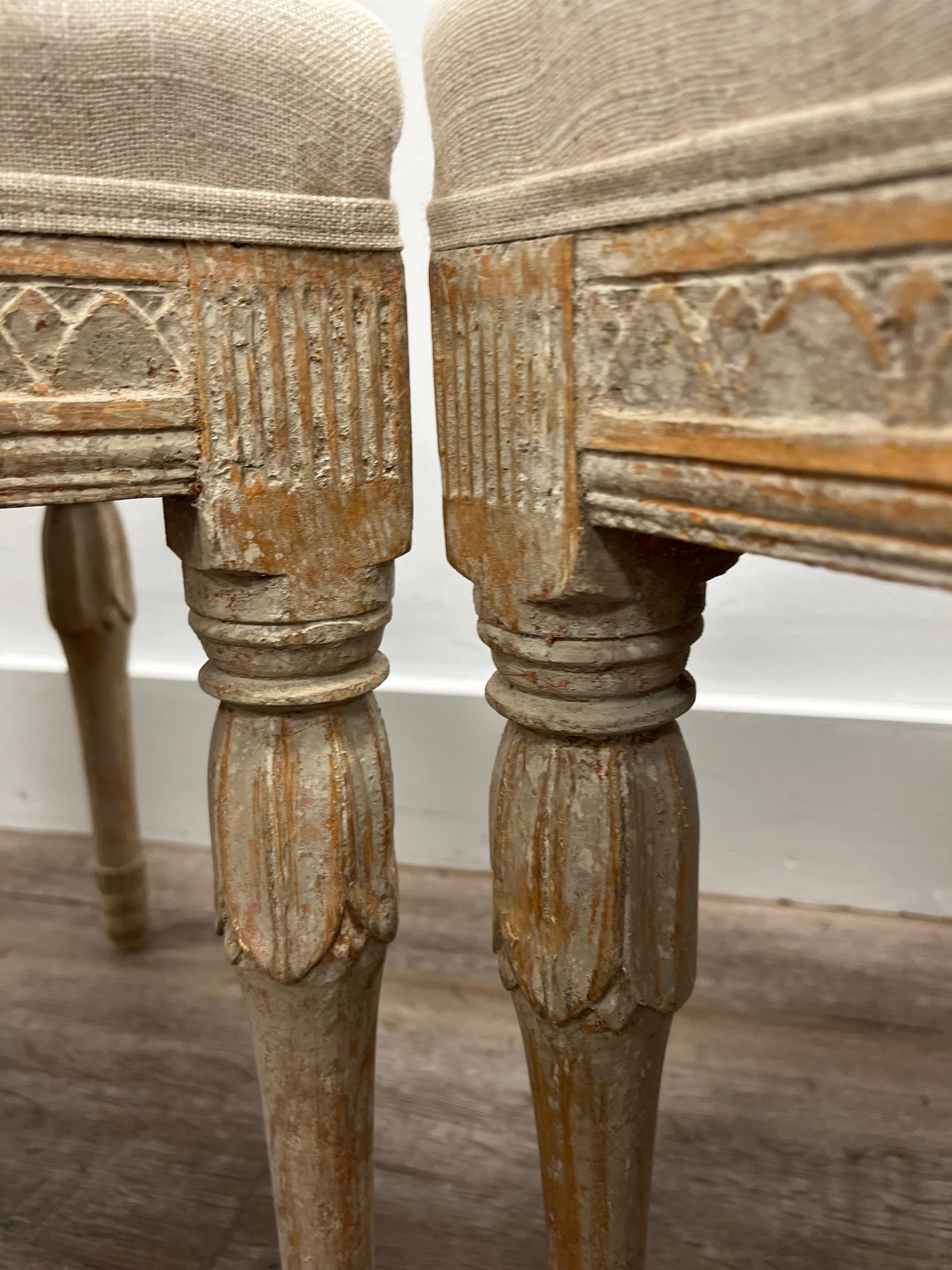 A beautiful pair of Swedish Gustavian footstools from Gotland. Leaf cut decor around the sides with reeded fleurons on the corners. The leg tops are finished with inverted pedals over turned and tapered bases. This piece has been tastefully