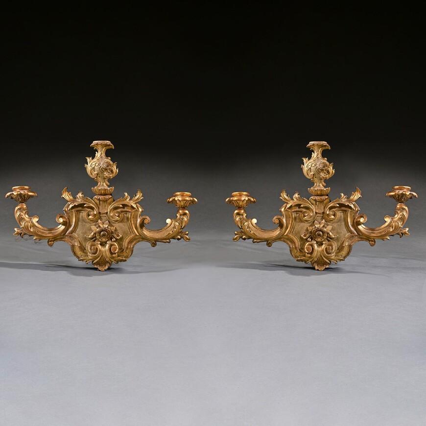 A very decorative and impressive pair of Italian Venetian giltwood wall sconces late 18th Century.

Italian circa 1780.

The two leaf carved up-scrolled candlebranches issuing from cartouche shaped panels carved with flowerhead and stylised vase
