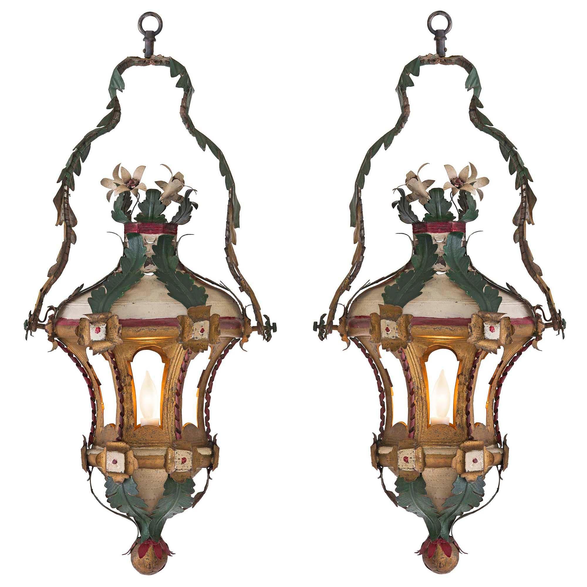 A very decorative pair of 18th century Venetian painted and gilt tole lanterns. The pair with a bottom gilt ball leads to 'S' scrolled green leaves with red tips. The hexagonally shaped band above has reserves at each corner. The six concaved open