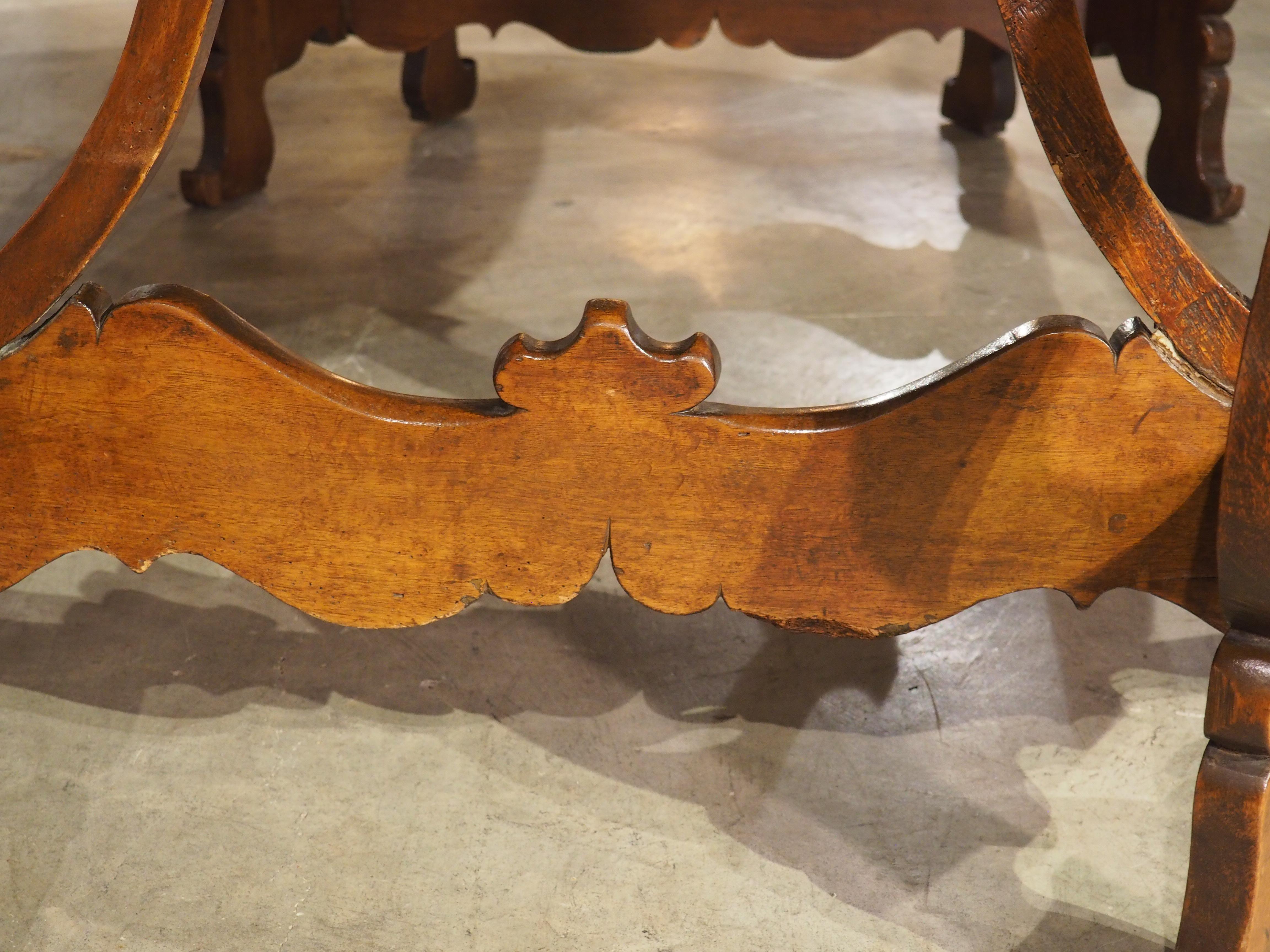 Le gambe a lira aperte e le barelle traforate sono caratteristiche delle consolle demi-lune della regione Piemonte, come si può vedere in questa coppia di tavoli in noce risalenti al 1700. Le gambe sinuose con i piedi a voluta sono esaltate dalla