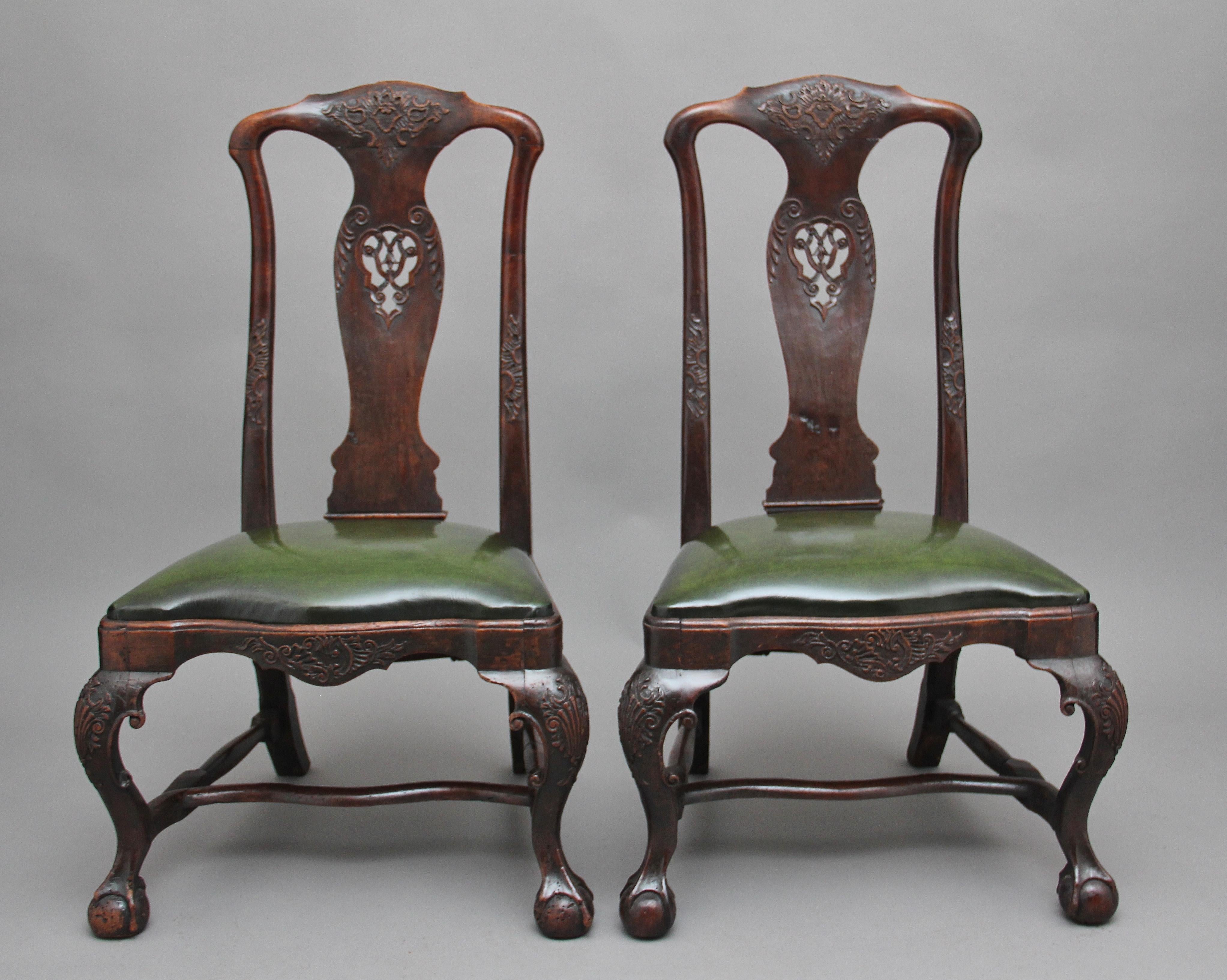 A rare pair of 18th century walnut Portuguese high back chairs, having tall carved and shaped backs, the shaped central splat having pierced and carved decoration, a green leather upholstered drop in seat with carved decoration on the seat frame,