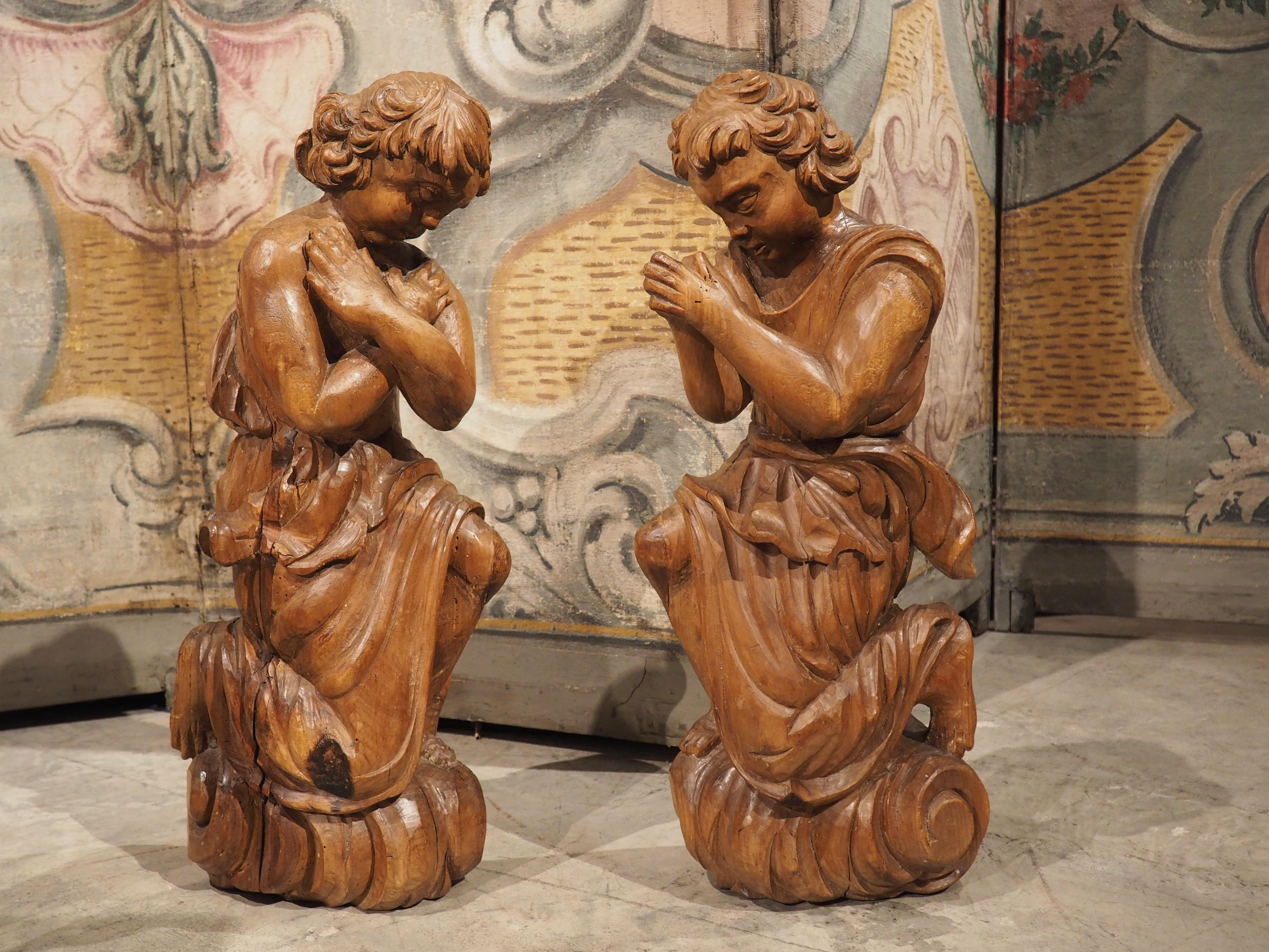 Hand-carved in the 1700’s in France, this pair of wooden angels are portrayed in similar genuflecting positions. One angel is depicted with right knee on the ground and arms crossed over the chest; the other one has the left knee down with hands