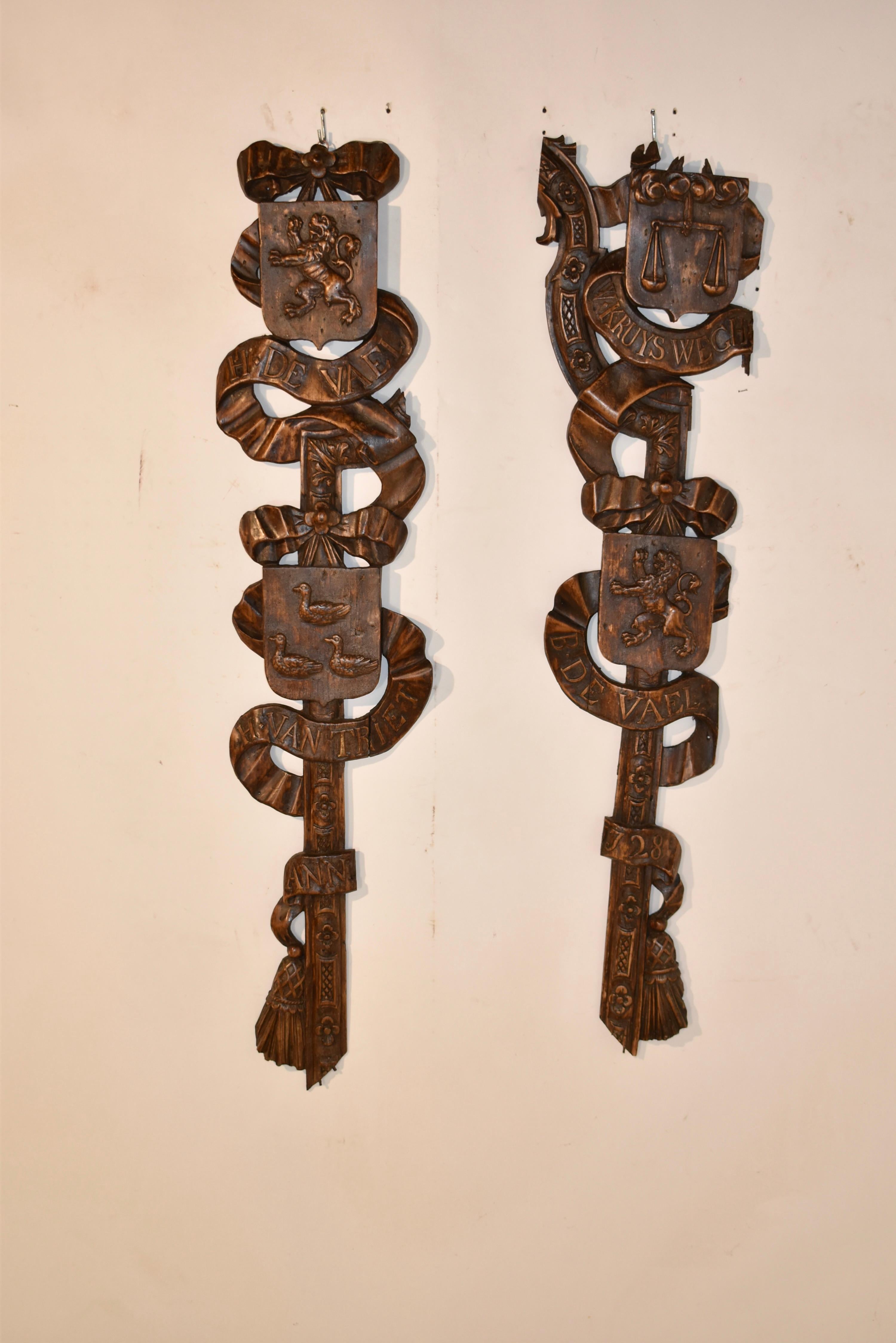Pair of hand carvings made from fruitwood that most likely came from a surround of a door in an 18th century home in the Netherlands.  The carvings  depict ribbons and carved moldings, like framing elements.  These include family names and armorial