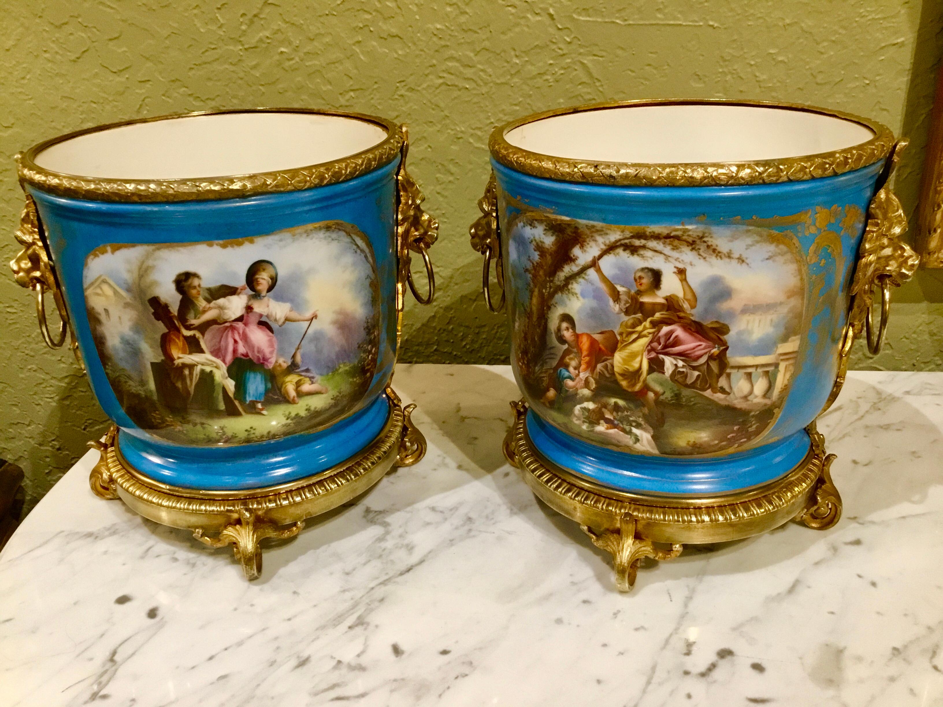 Antique pair of Sevres Porcelain cache pots with neoclassical garden scenes painted
On the front reserves of these pieces and flowers on the verso, 19th century. They are mounted on
Gilt bronze bases and have a gadrooned edge of gilt bronze on the