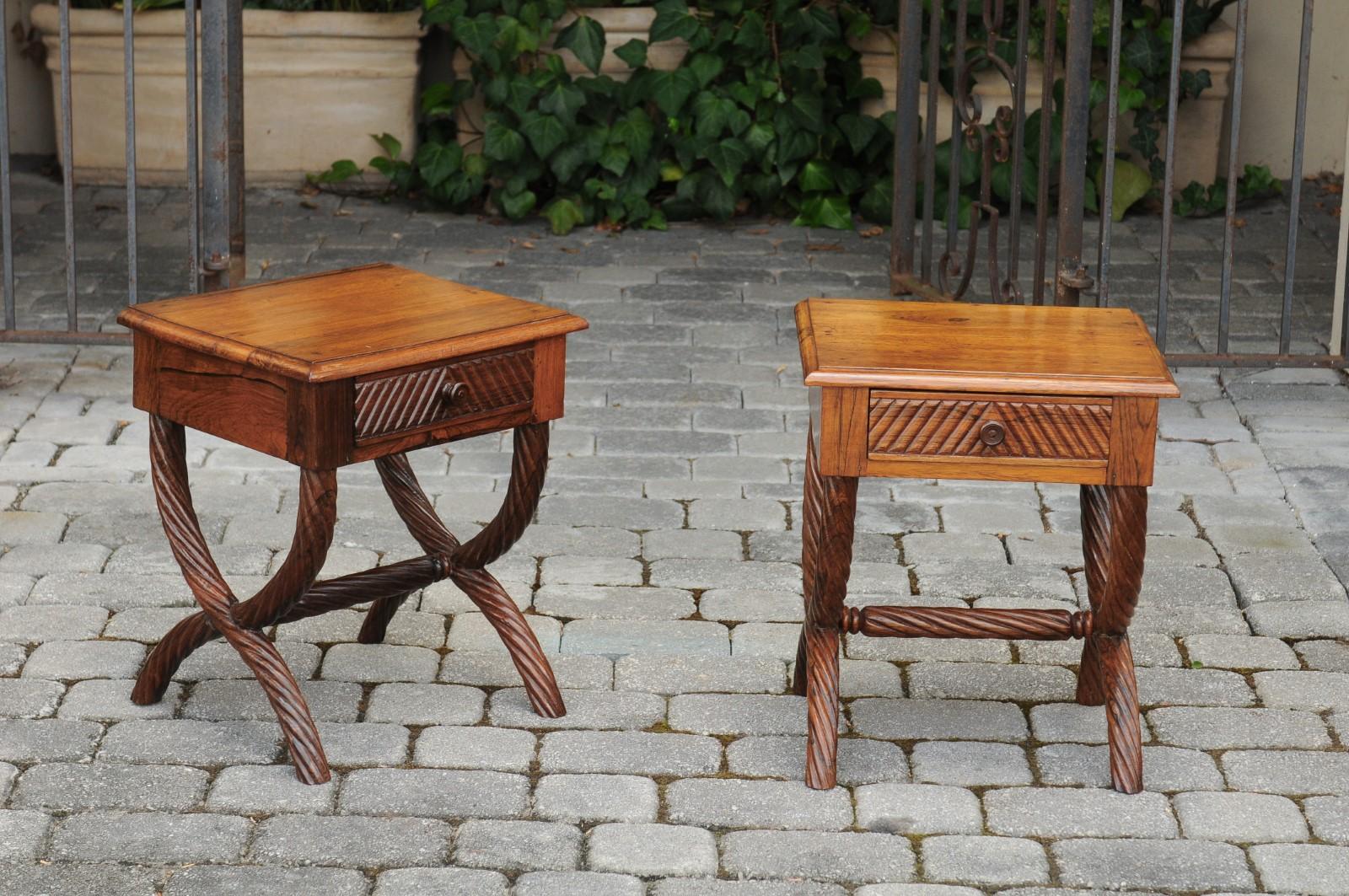 A pair of Anglo-Indian low side tables from the early 20th century, with Curule bases and twisted accents. Born in the early 1900s, each of this pair of Anglo-Indian low tables features a rectangular top sitting above an apron presenting a single