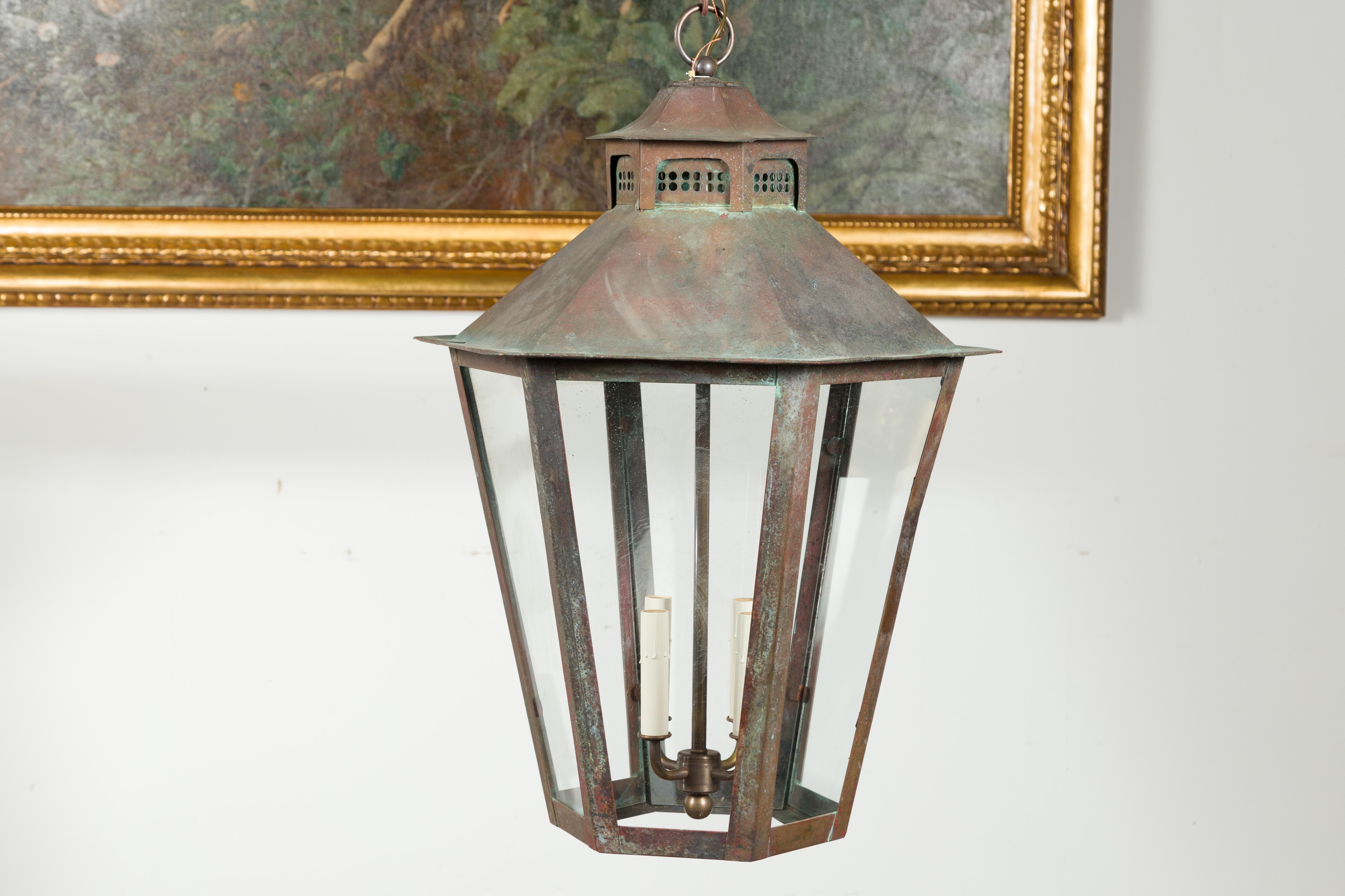A pair of English turn of the century four-light hexagonal copper lanterns from the early 20th century, with glass panels. Created in England during the turn of the century, each of this pair of copper lanterns attracts our attention with their