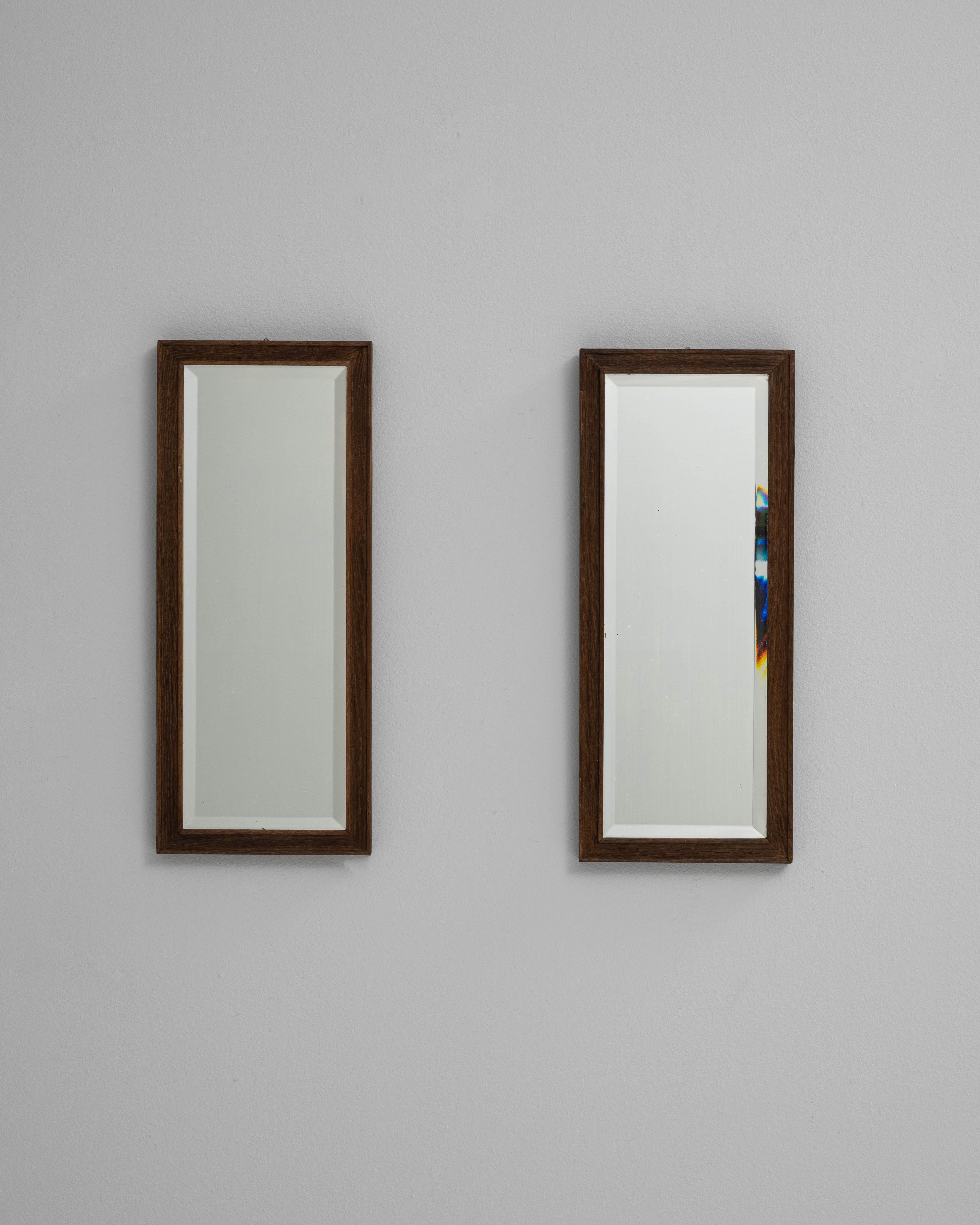 Coppia di specchi francesi in legno del 1900. Questa elegante coppia di specchi francesi dell'inizio del XX secolo presenta un design raffinato e sobrio che enfatizza le linee pulite e i caldi materiali naturali. Ogni specchio è incorniciato in