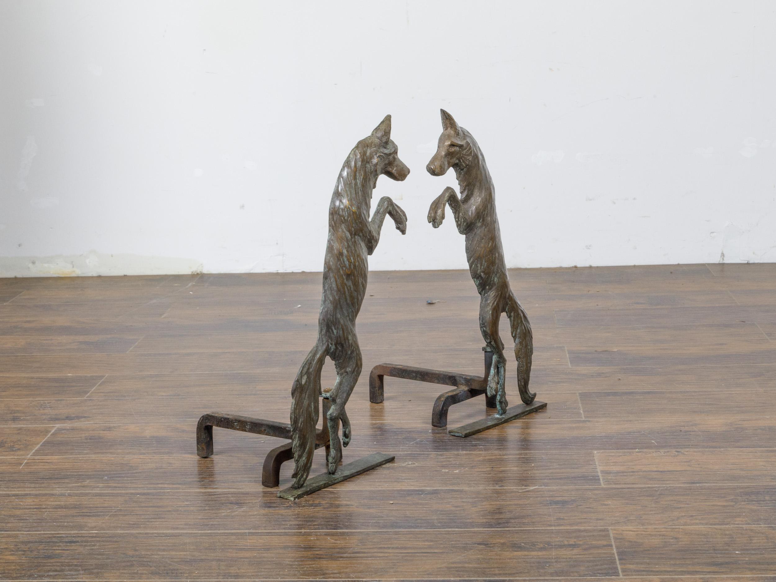 A pair of American Turn of the Century bronze andirons from circa 1900 depicting two wolves standing on their hind legs. This striking pair of American Turn of the Century bronze andirons from circa 1900 is a captivating representation of two