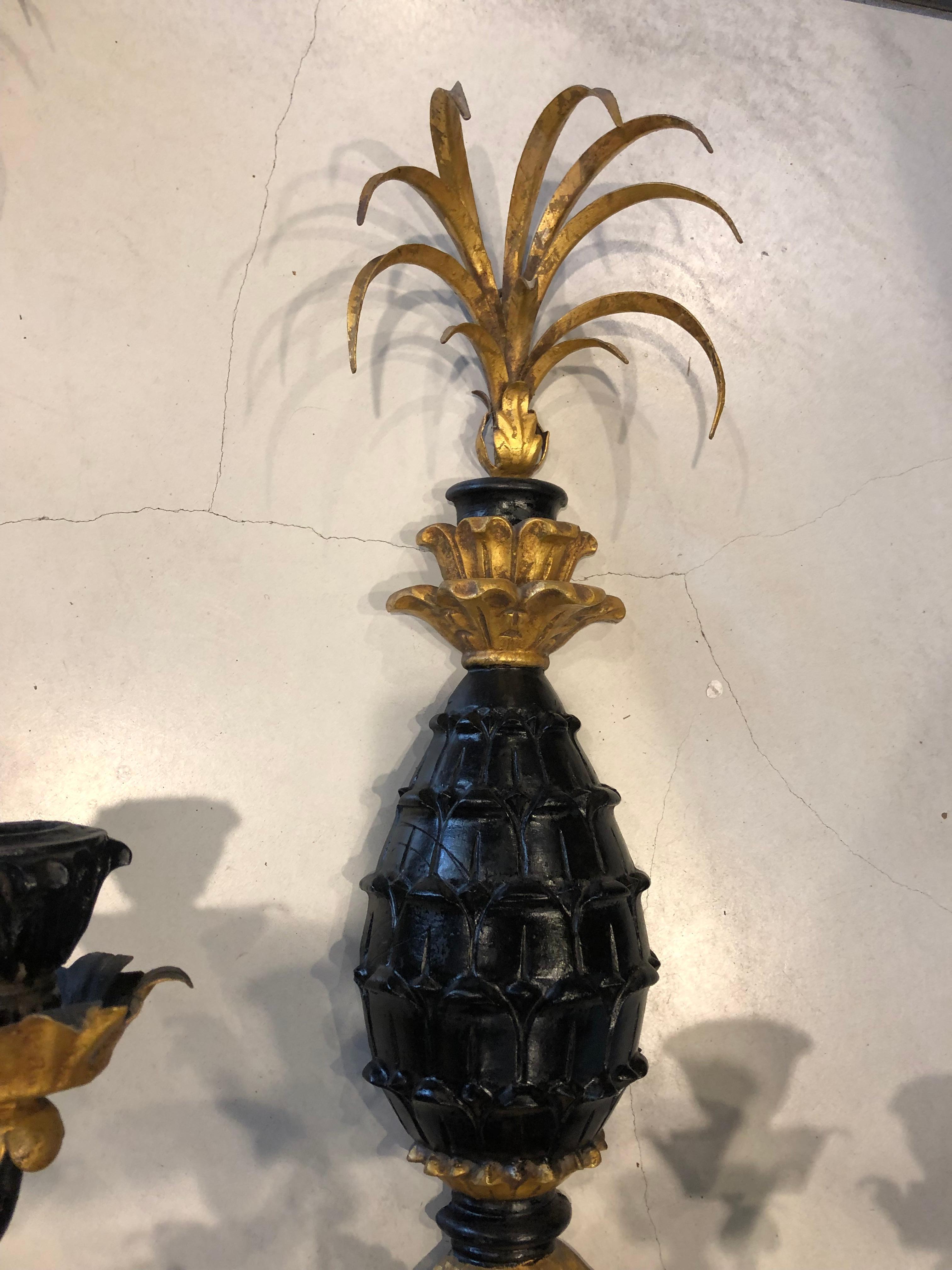 The pair of sconces being hand carved of wood, hand painted black and gold leaf and electric 3 arm with tulip shaped candle holders metal plume in gold.