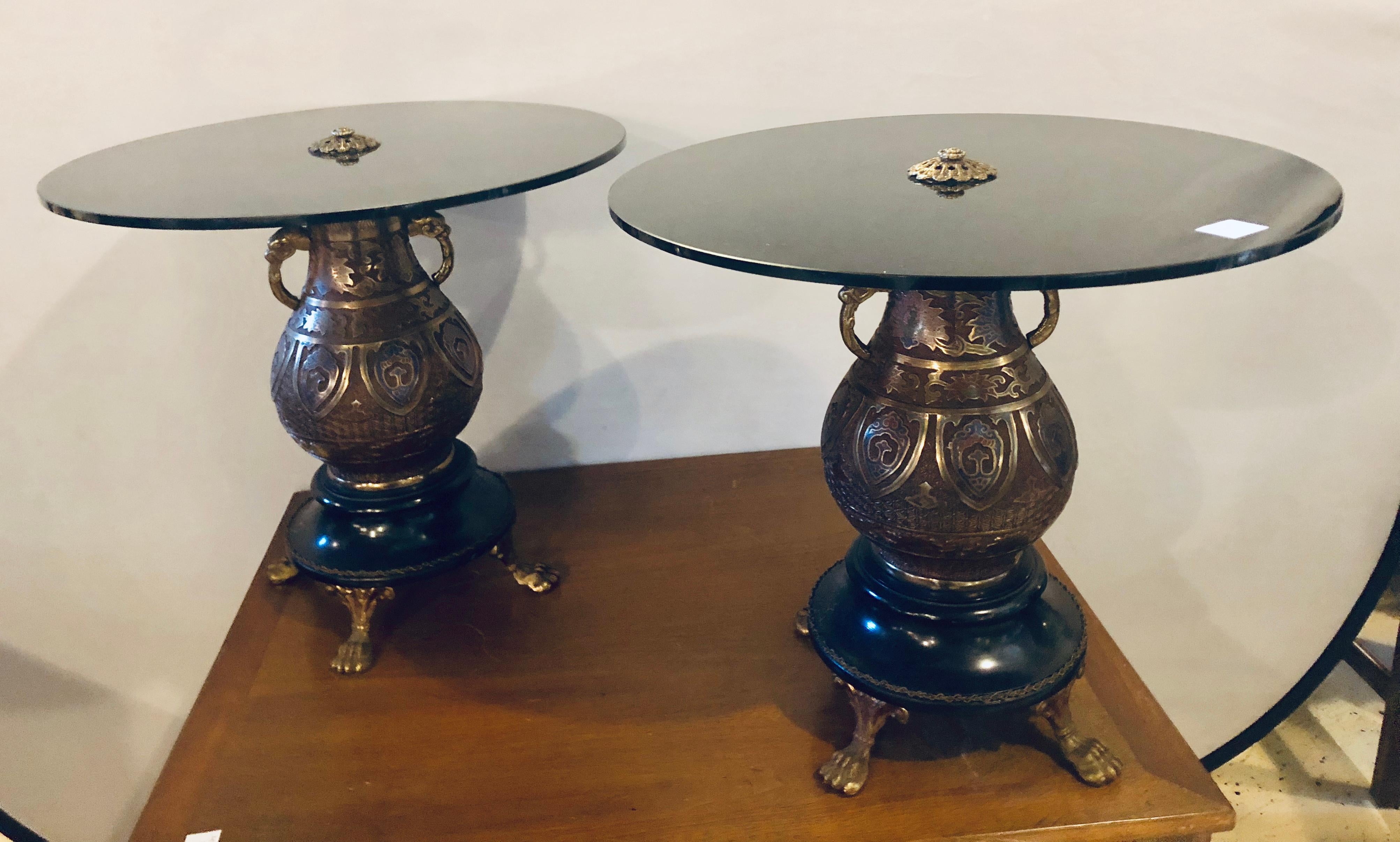 A pair of bronze urn form glass top end tables. Each Chinese inspired end table has a chinoiserie urn on a marble base and bronze feet supporting a black glass circular table top. Sitting side by side these make a lovely coffee table.