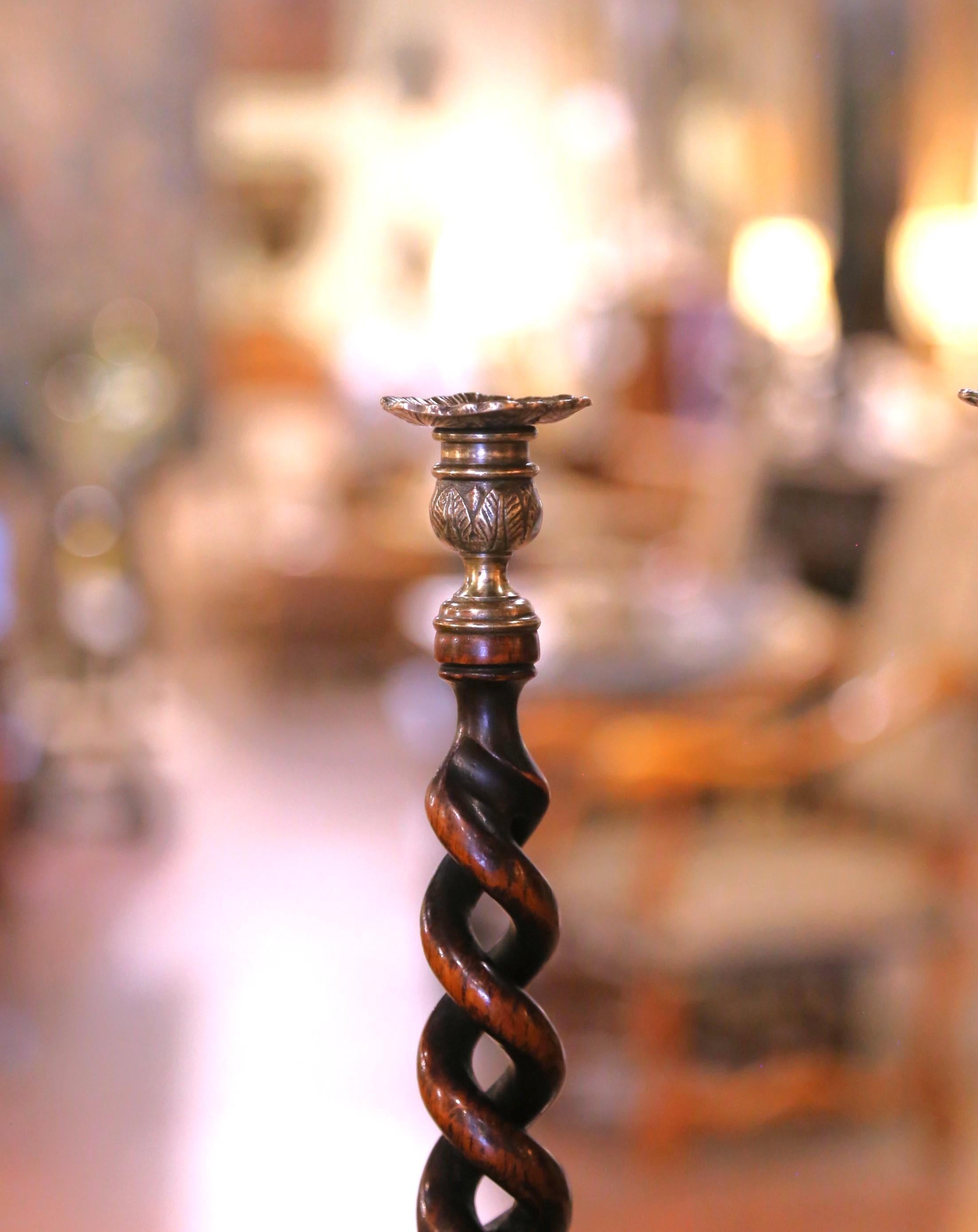 Ces chandeliers anciens ont été fabriqués en Angleterre vers 1920. Posé sur une base ronde, chaque bougeoir est doté d'une tige torsadée en orge percée et sculptée, ornée d'un fleuron en laiton au sommet. Les deux grands chandeliers sont en