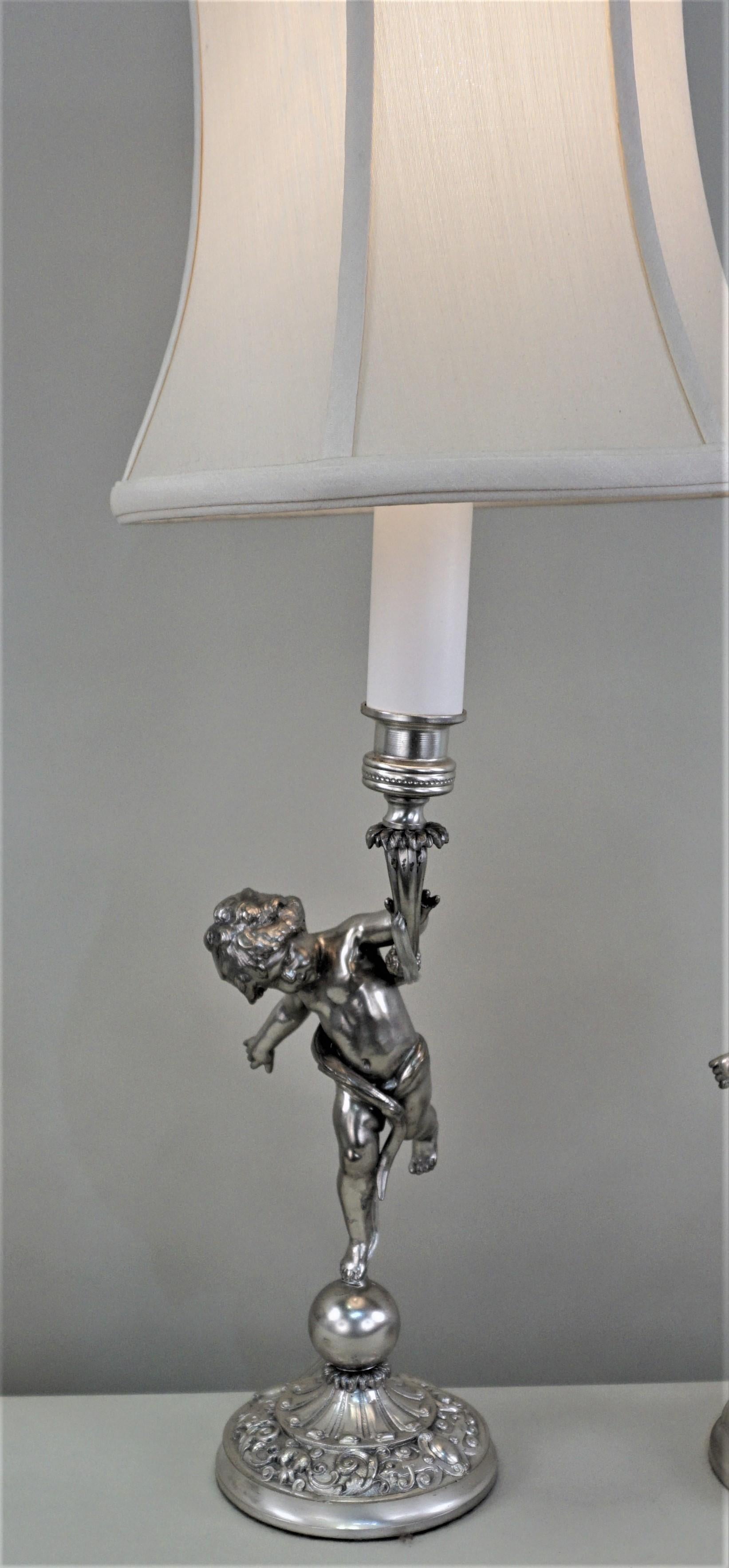 Beautiful pair of silver on bronze candlestick that has been electrified as table lamps and fitted with silk lampshades.
24