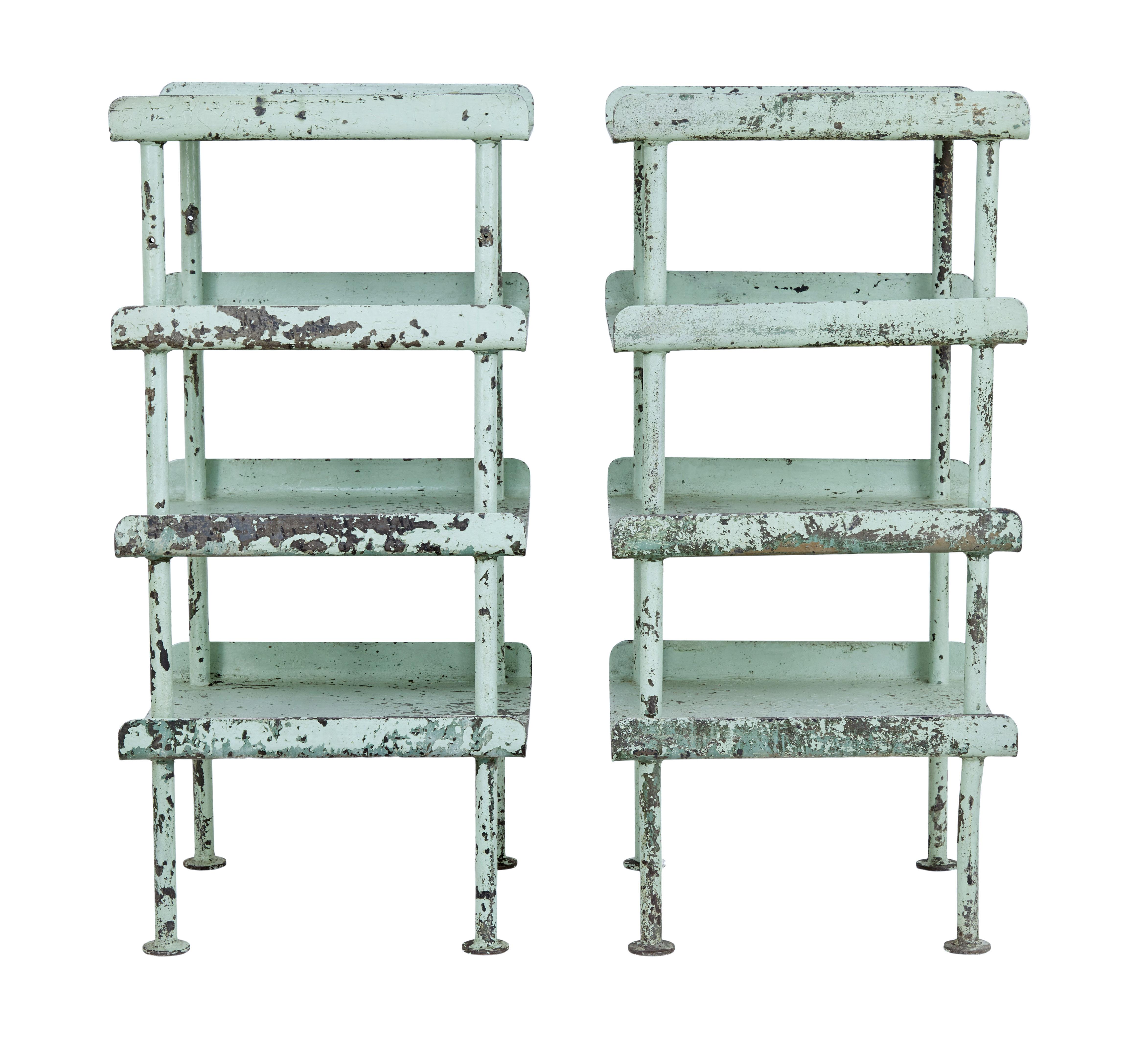 Pair of 1920s industrial steel storage stands, circa 1920.

Pair of 4-tier stands with curved edges to the sides, supported by tubular legs. Obvious losses to paint work and some bending with minor fractures.

Ideal for use in a garden room or