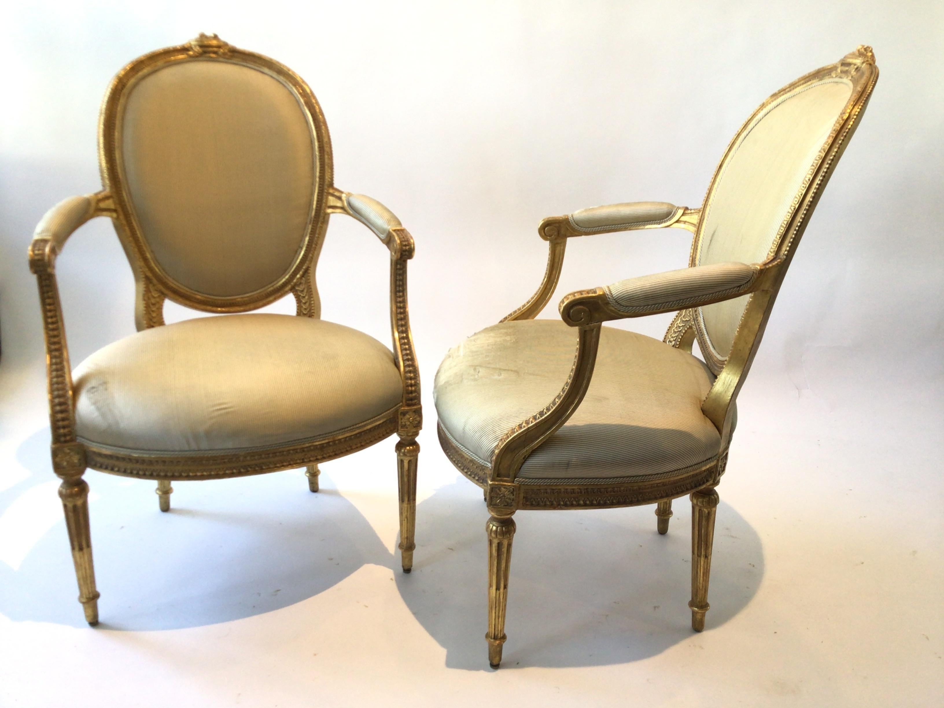 Pair of 1920s French gilt wood hand carved Louis XVI armchairs. Needs reupholstering. Purchased from a 15 million dollar Southampton home.