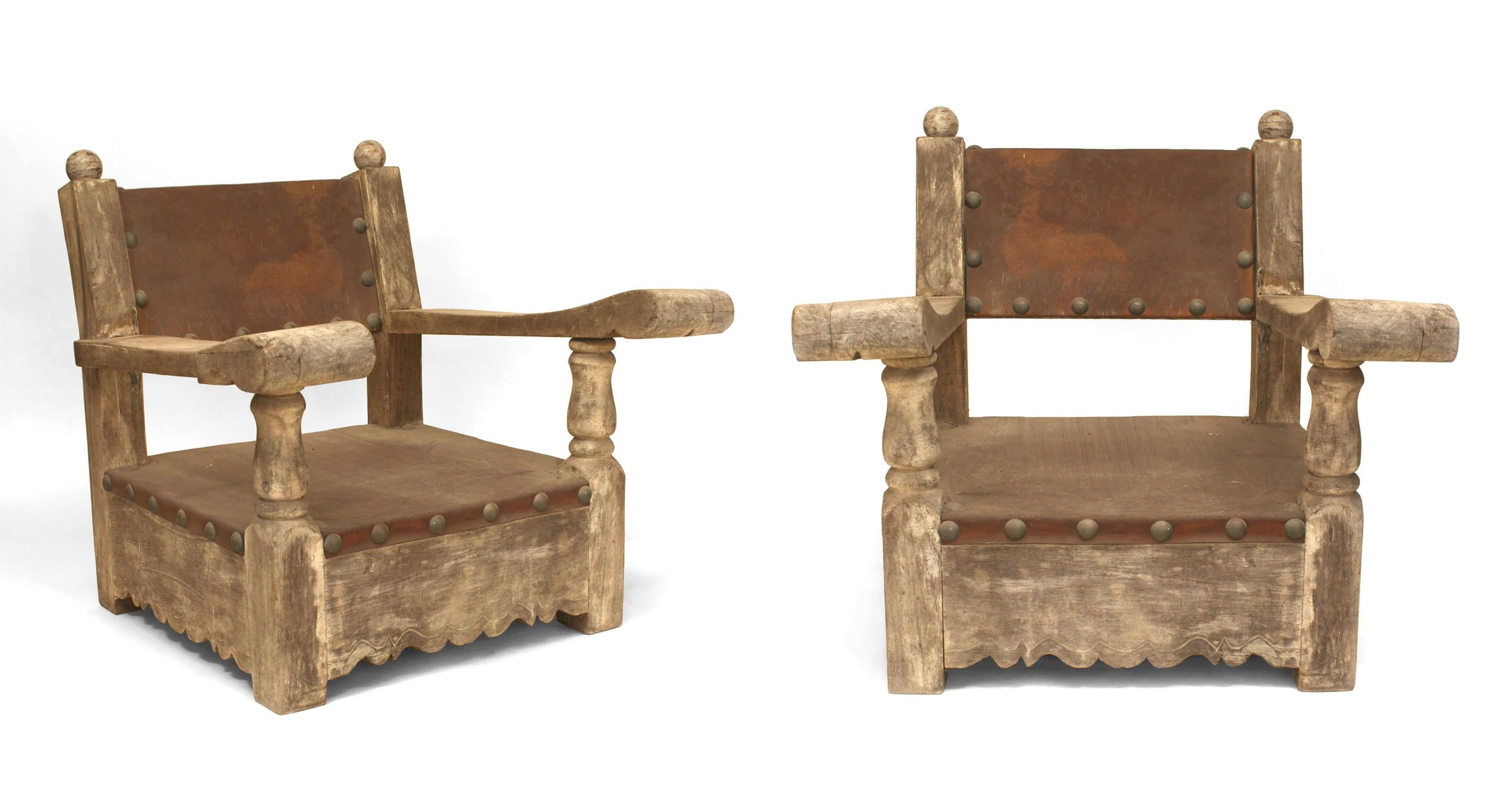 Paire de fauteuils rustiques (probablement du Mexique des années 1920) en chêne et pin patinés par le temps, avec assise et dossier en cuir brun et garniture de têtes de clous.

