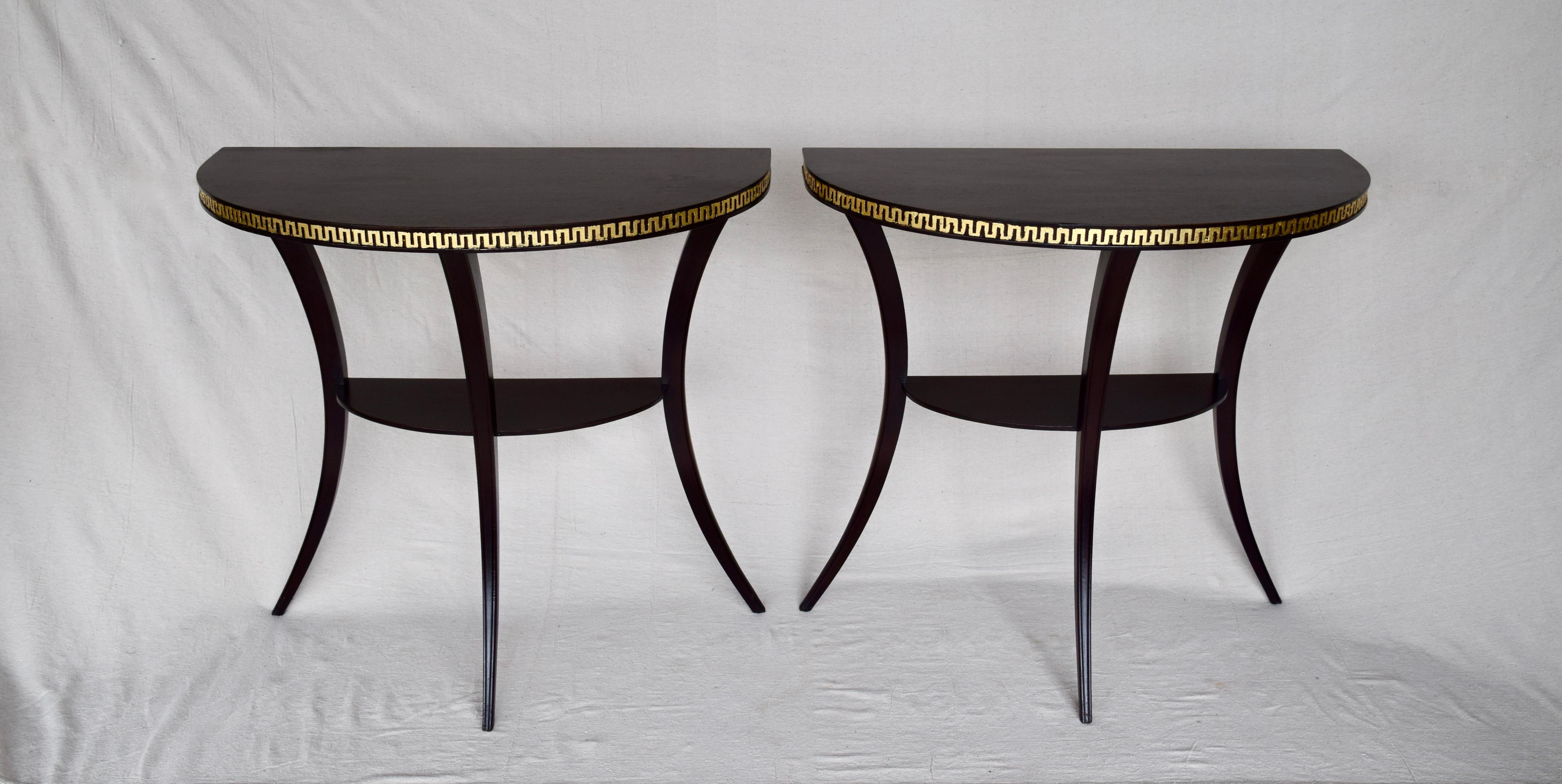 Striking 1920s demilune semi-circular single shelf tables with saber Klismos legs and Greek key styling. The tables are refinished and embellished with 24-karat gold distressed style hand gilt surrounds.
 