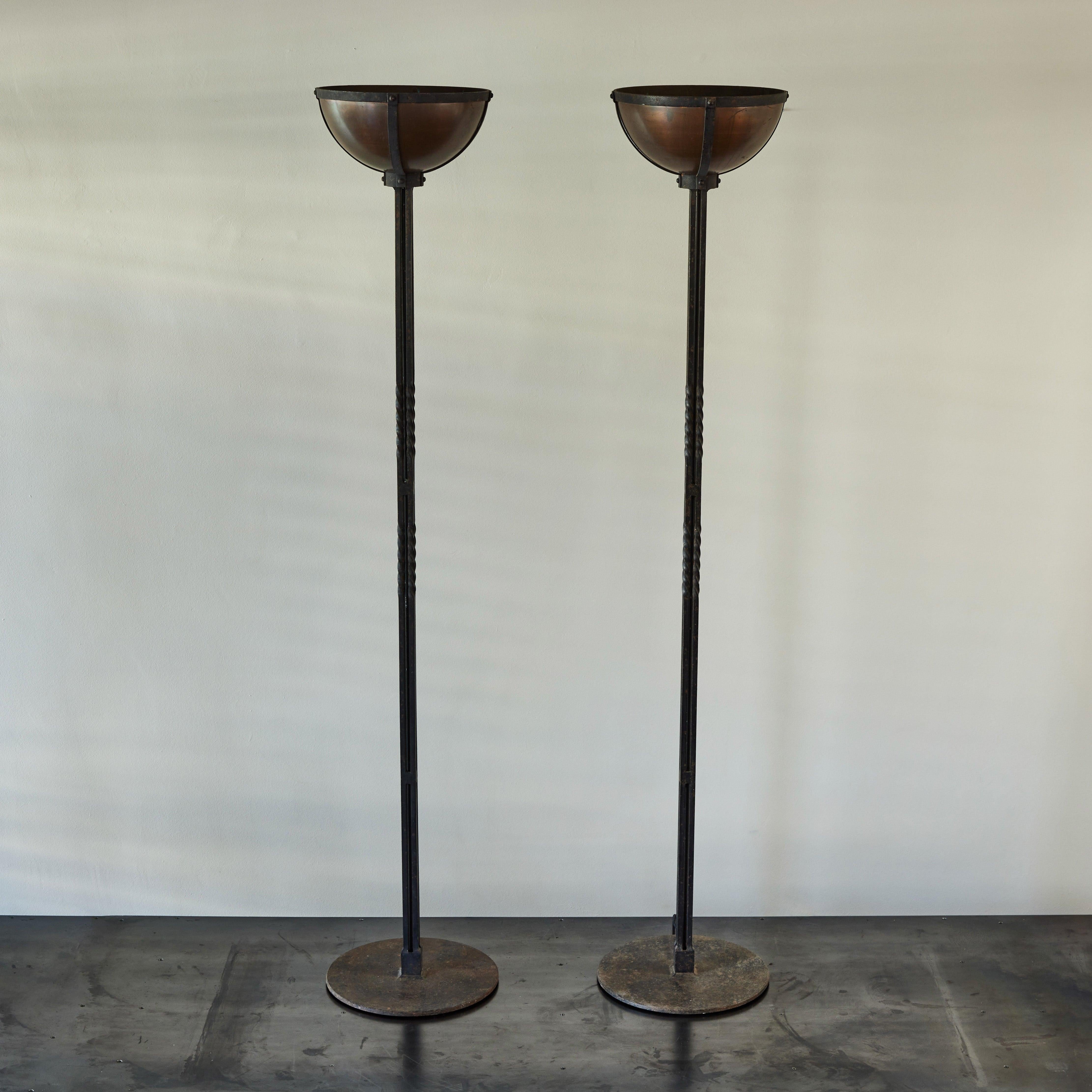 Pair of 1920s Spanish cast-iron floor lamps. Striking and unique, the pair features beautifully turned stems and brass uplighting shades. A dramatic lighting arrangement with a Gothic Revival feel. 

Dimensions: 14W x 14D x 79H.