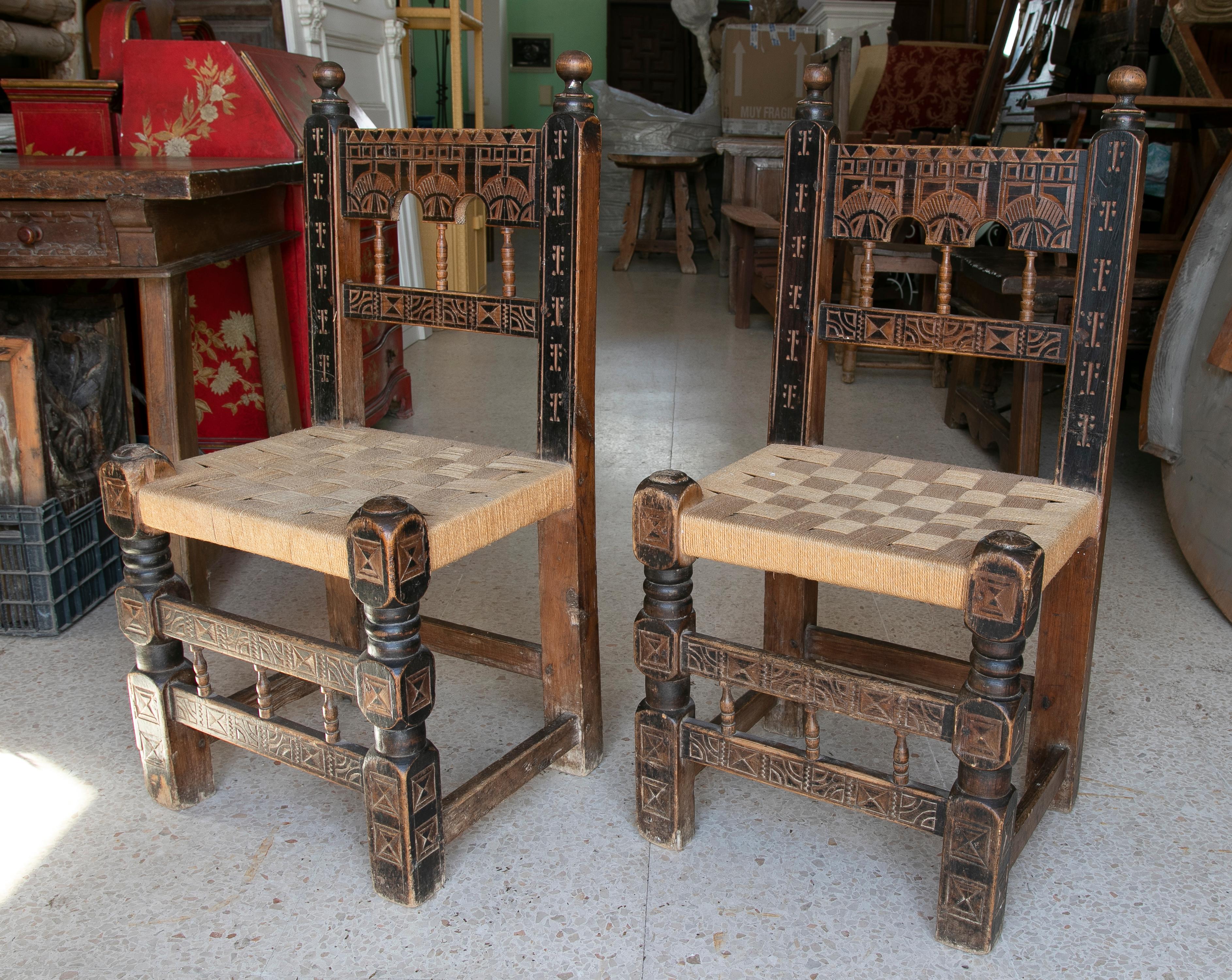 Pair of 1920s Spanish hand carved painted wooden chairs w/ woven bulrush seats.