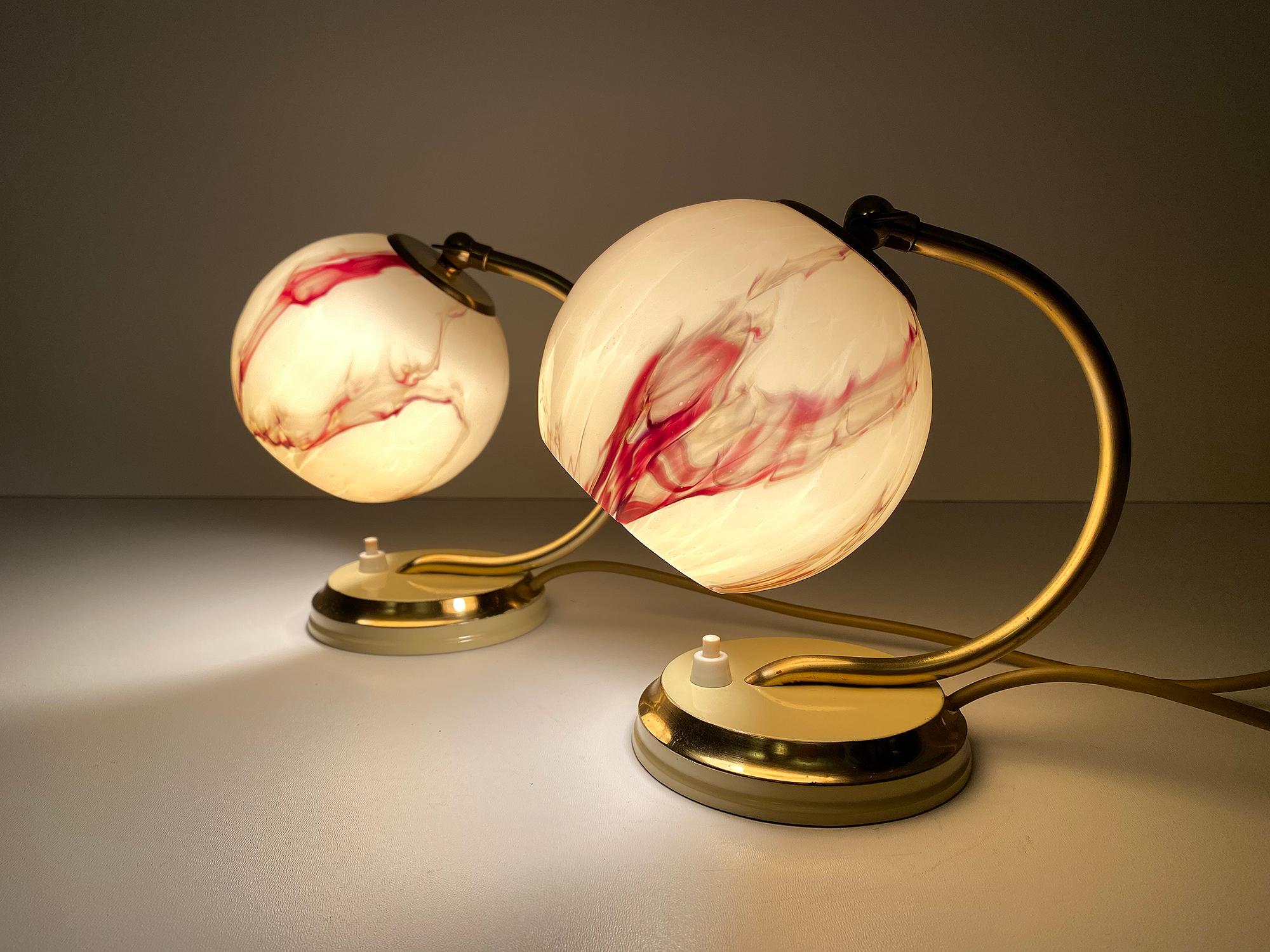 Pair of Art Deco table lamps, featuring a cream white enameled base with brass trim, polished brass cradle shaped stems and caps with cream white trim, absolutely stunning marbleized opaline glass shades, overlay glass, cream white with oxblood