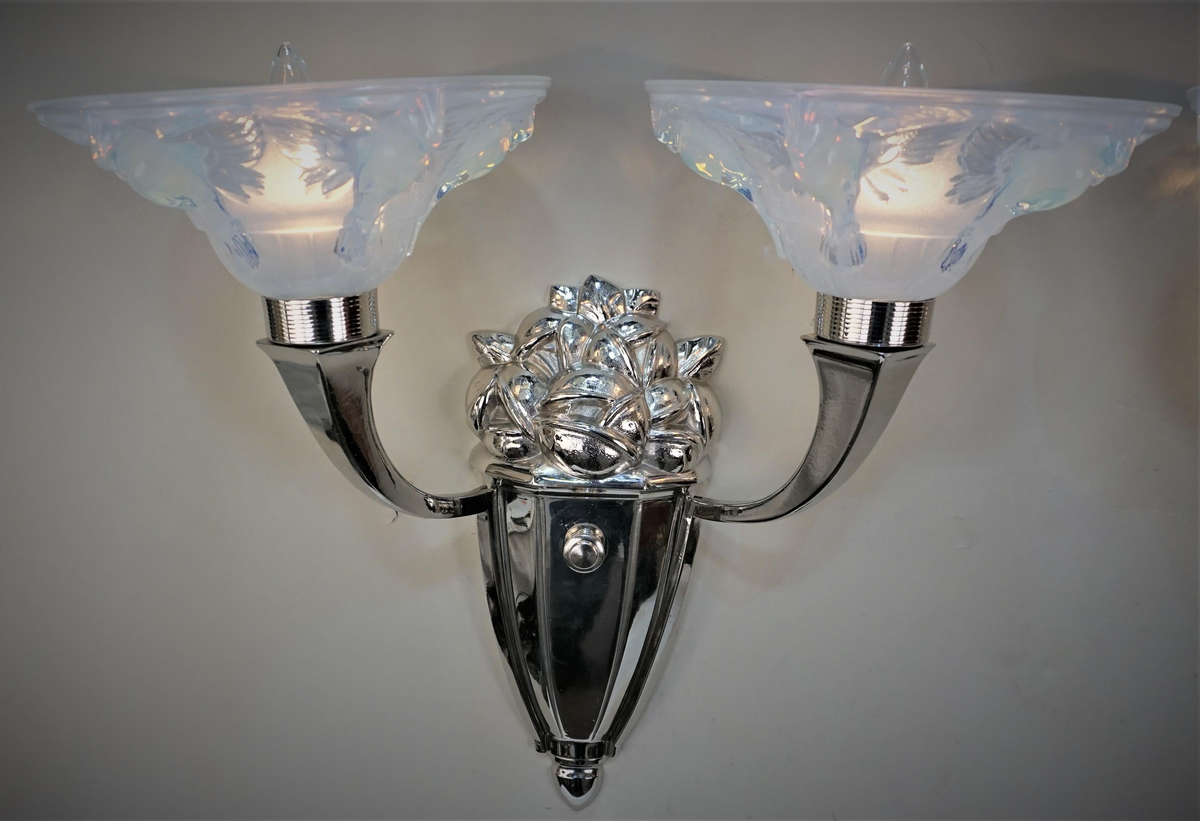 Paar doppelarmige Wandleuchter aus Nickel auf Bronze mit honigblauen Opalglasschirmen, fliegender Vogel.
Professionell neu verkabelt und einbaufertig.
Maximal 60 Watt pro Leuchte.