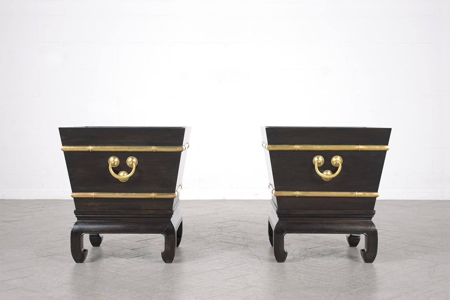 Experience the timeless allure of our pair of early 1900s Chinese garden planters, skillfully restored by our in-house team of professional craftsmen. Crafted from wood and brass, these vintage planters showcase an elegant ebonized color, finished