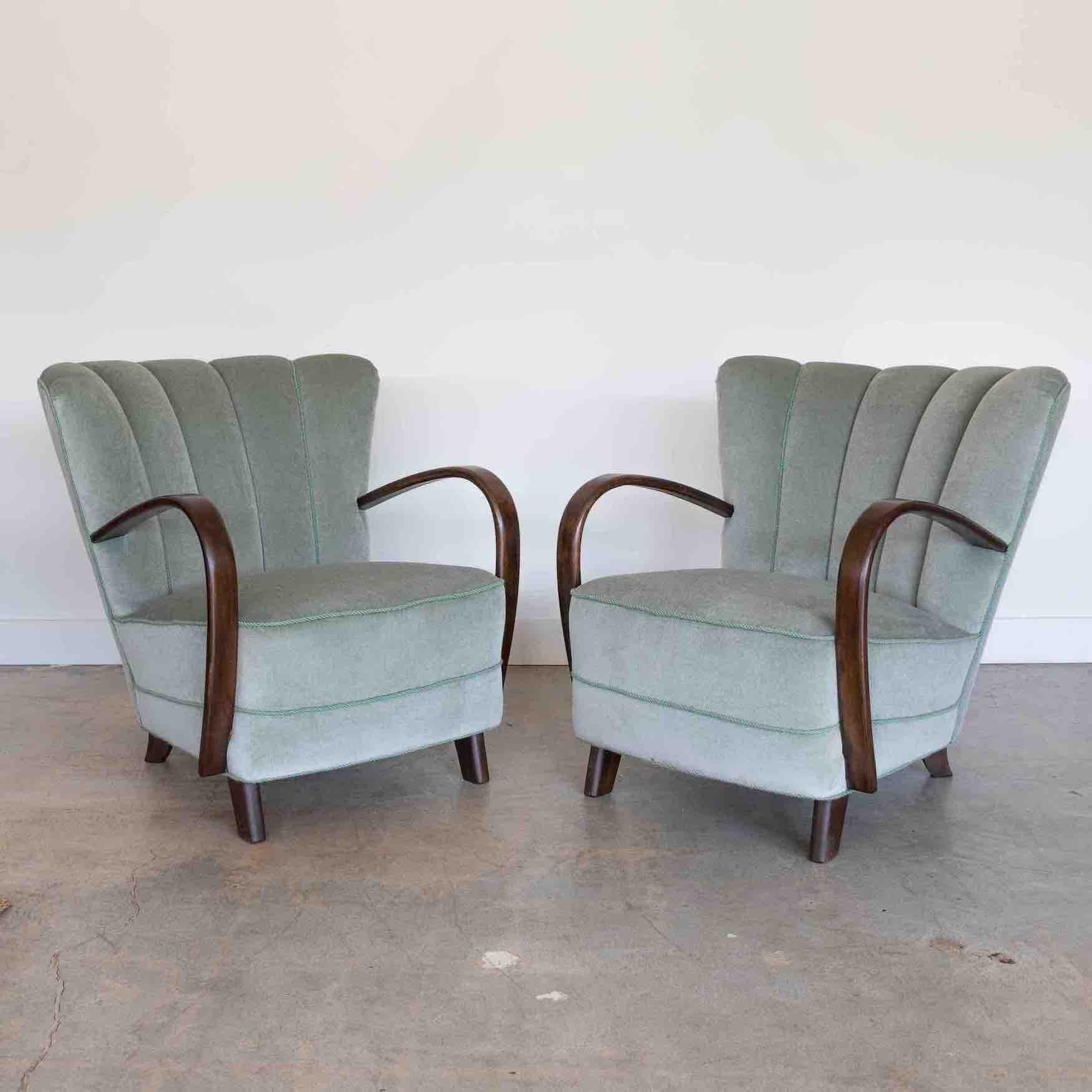 Stunning pair of upholstered Art Deco lounge chairs from Denmark, 1930's. Newly upholstered in soft seafoam green Italian mohair with complimentary piping detail. Beautifully curved wood arms and wood tapered feet in dark stain. Incredible pair of