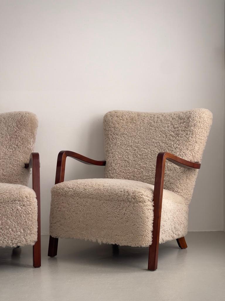 Danois Paire de chaises longues danoises des années 1930 en hêtre teinté, retapissées en shearling. en vente